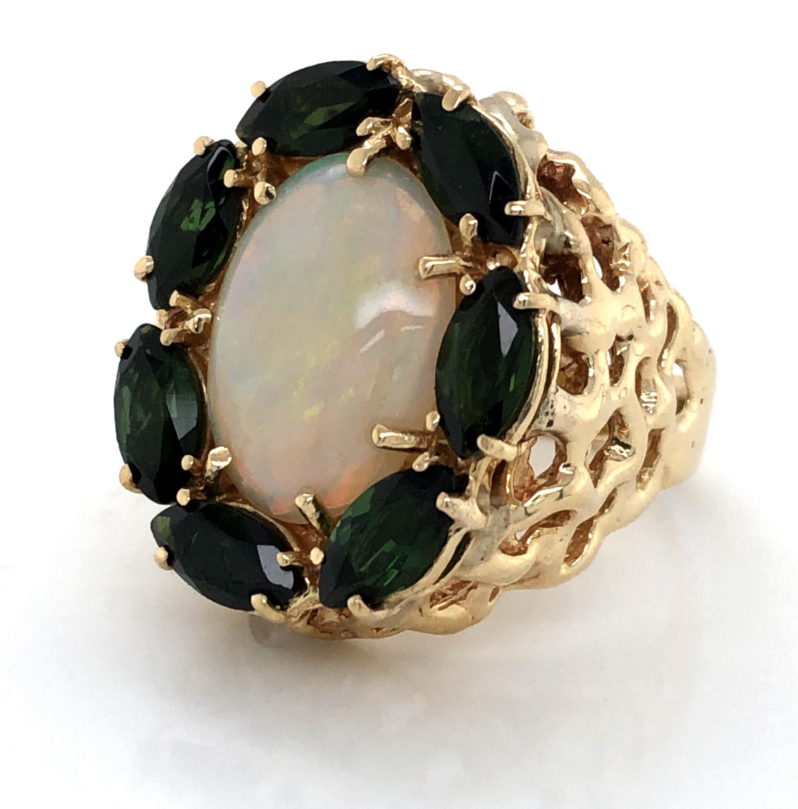 Seven rich green faceted marquise cut peridot stones, two carat total weight, dance around the large featured 17mm x 13mm oval iridescent opal cabochon that is the focal point of this statement ring. A substantial basket weave inspired ring shoulder