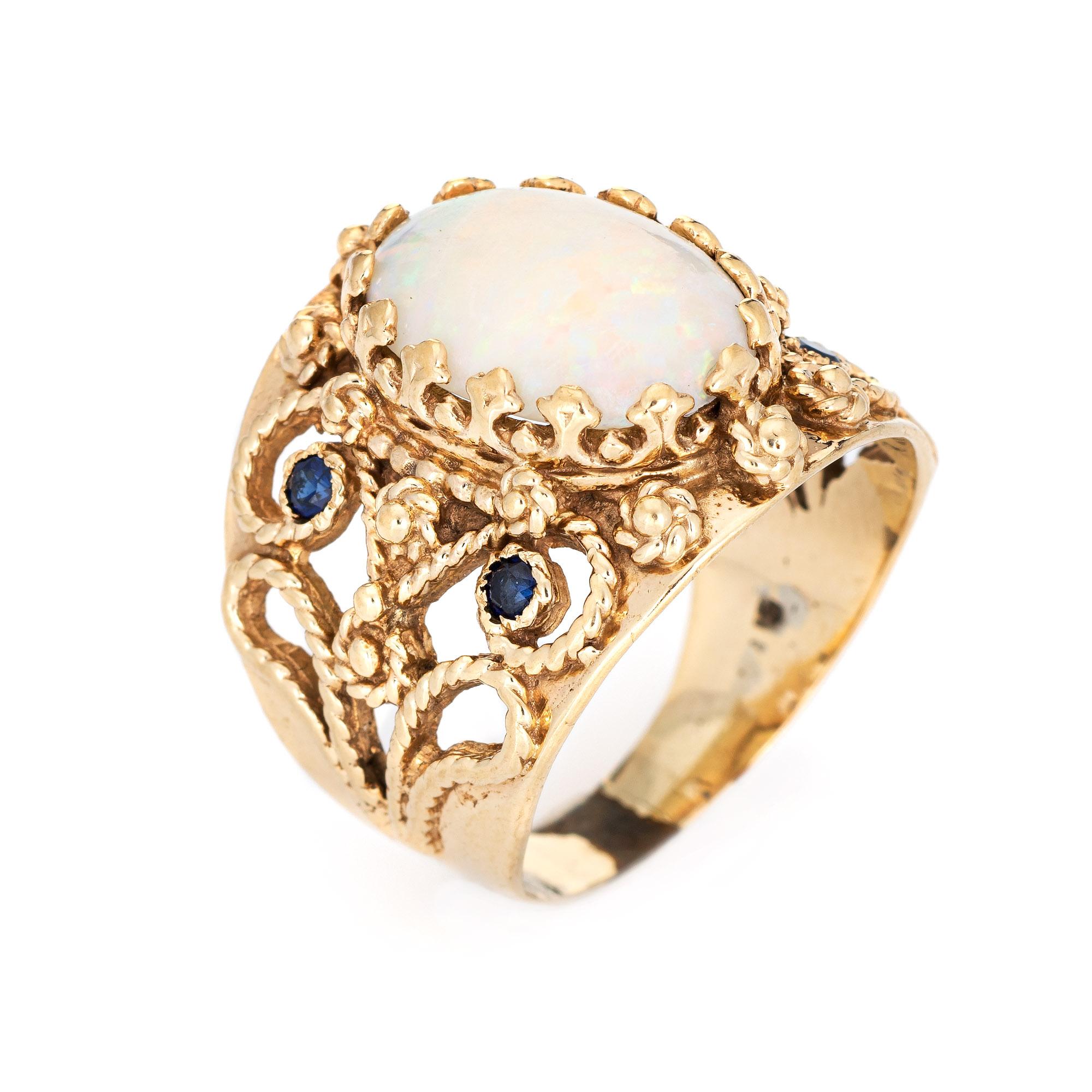 Stylish vintage opal & sapphire ring (circa 1960s to 1970s) crafted in 14 karat yellow gold. 

Natural opal measures 14mm x 10mm (estimated at 2.25 carats). The opal is in very good condition and free of cracks or chips. Four sapphires total an