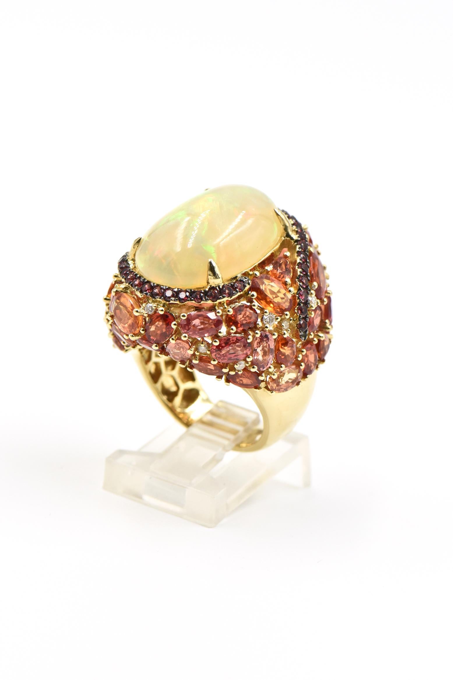 Beautifully made 18k yellow gold cocktail ring featuring a prong set 9.18 carat opal set in a pink sapphire swirl that leads to a cascade of faceted vitrines with .16 carats of diamond accents.  This ring is truly spectacular even the back has a
