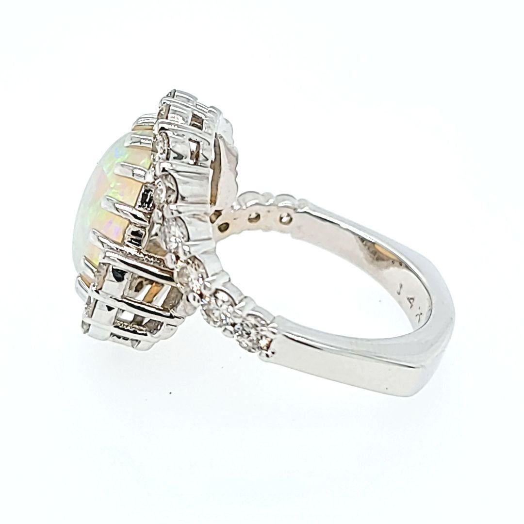 14 Karat White Gold Cocktail Ring Featuring A 13mm x 10mm Oval Opal Cabochon with Green Play of Color, Surrounded By 22 Round Brilliant Cut Diamonds of SI Clarity and G/H Color Totaling 1.00 Carat. Euroshank Design Finger Size 8.25. Purchase