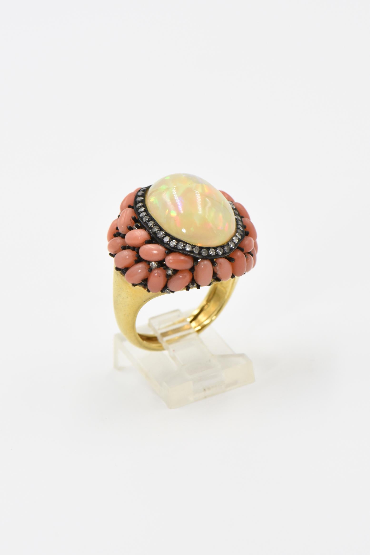 Dieser hochgradig stilisierte Ring zeigt einen Cabochon aus äthiopischem Opal in der Mitte einer diamantbesetzten Fassung mit eingestreuten Korallen und Diamanten an den Rändern der Oberseite.  Der Ring ist aus Sterlingsilber mit