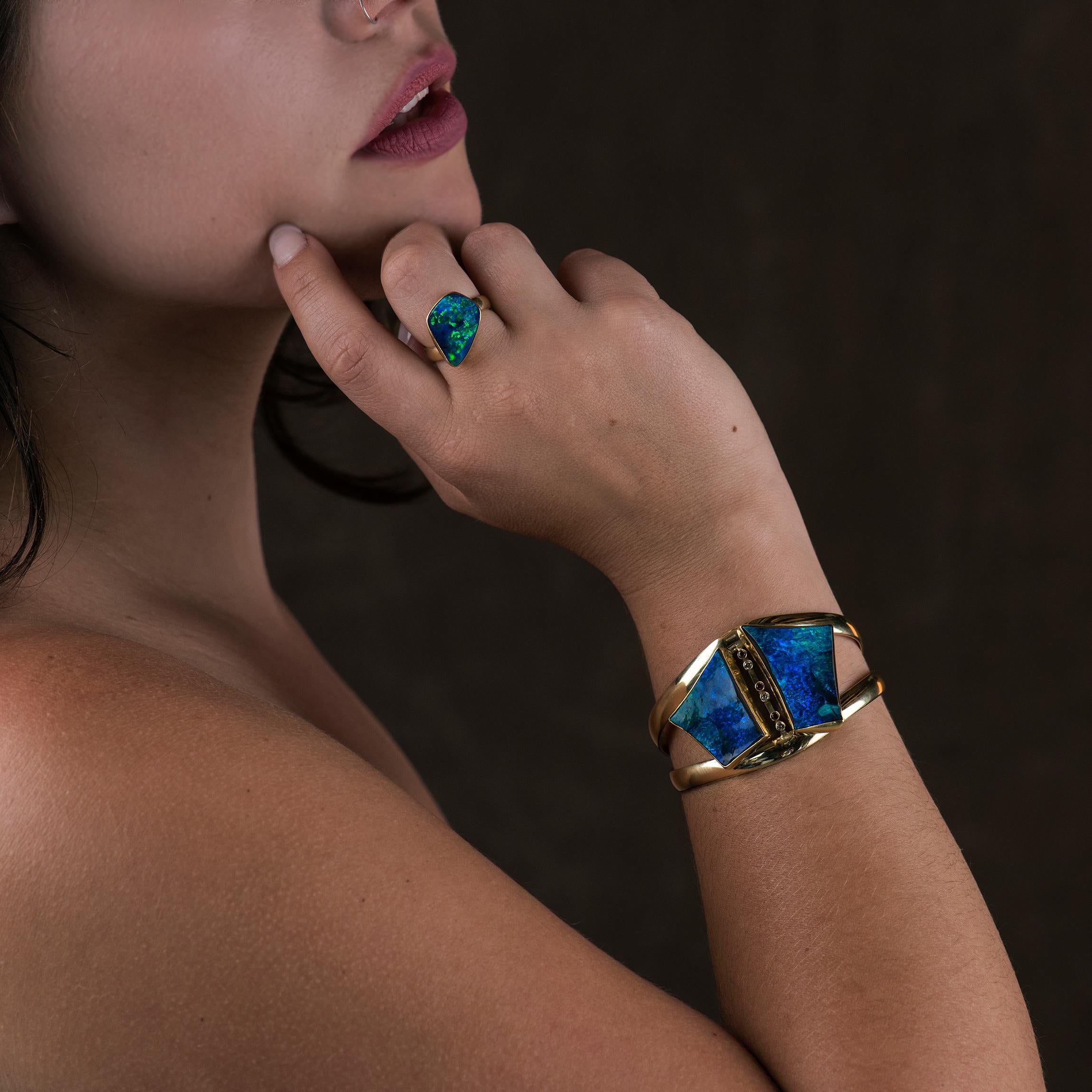 Classic and classy blue green boulder opal, cut in unique shapes, and fabricated into a weighty gold cuff of 22k and 18k gold.  The cuff bracelet is accented with diamonds and champagne zircons.  The boulder opal rough had such a large clean face of