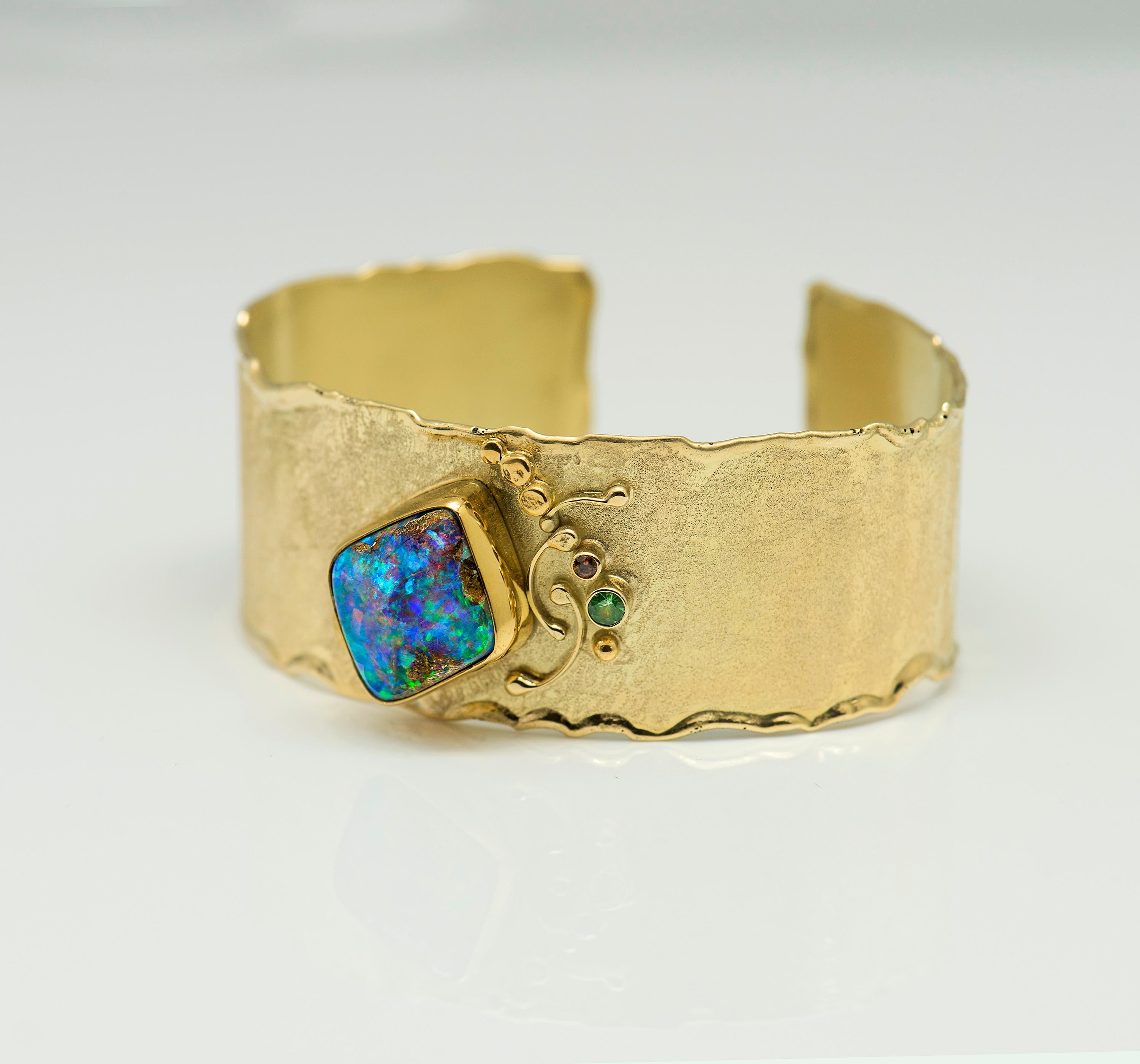   This Cuff is designed in 18k gold, the bezel around the opal is 22k gold.  The Cuff can be sized, it's a large currently, but can be sized to your preference.  The color tones in the opal are beautiful blues, greens and a periwinkle hue.  Opalized