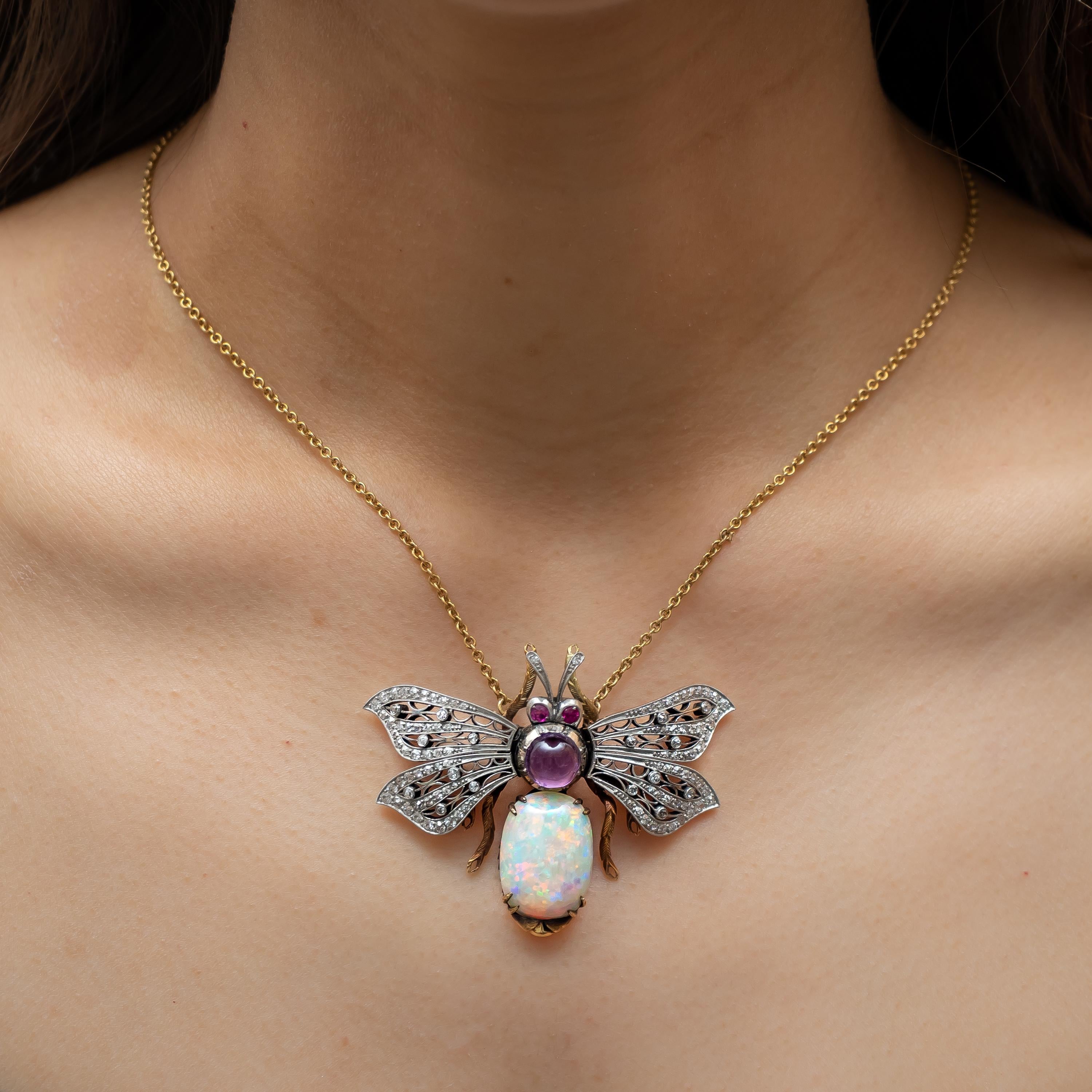 A gem set bee pendant, with an oval cabochon cut opal and a round cabochon cut amethyst set to the body, articulating wings, set with eight-cut diamonds, and ruby eyes, on a trace chain, mounted in gold, with white gold settings for the diamonds.