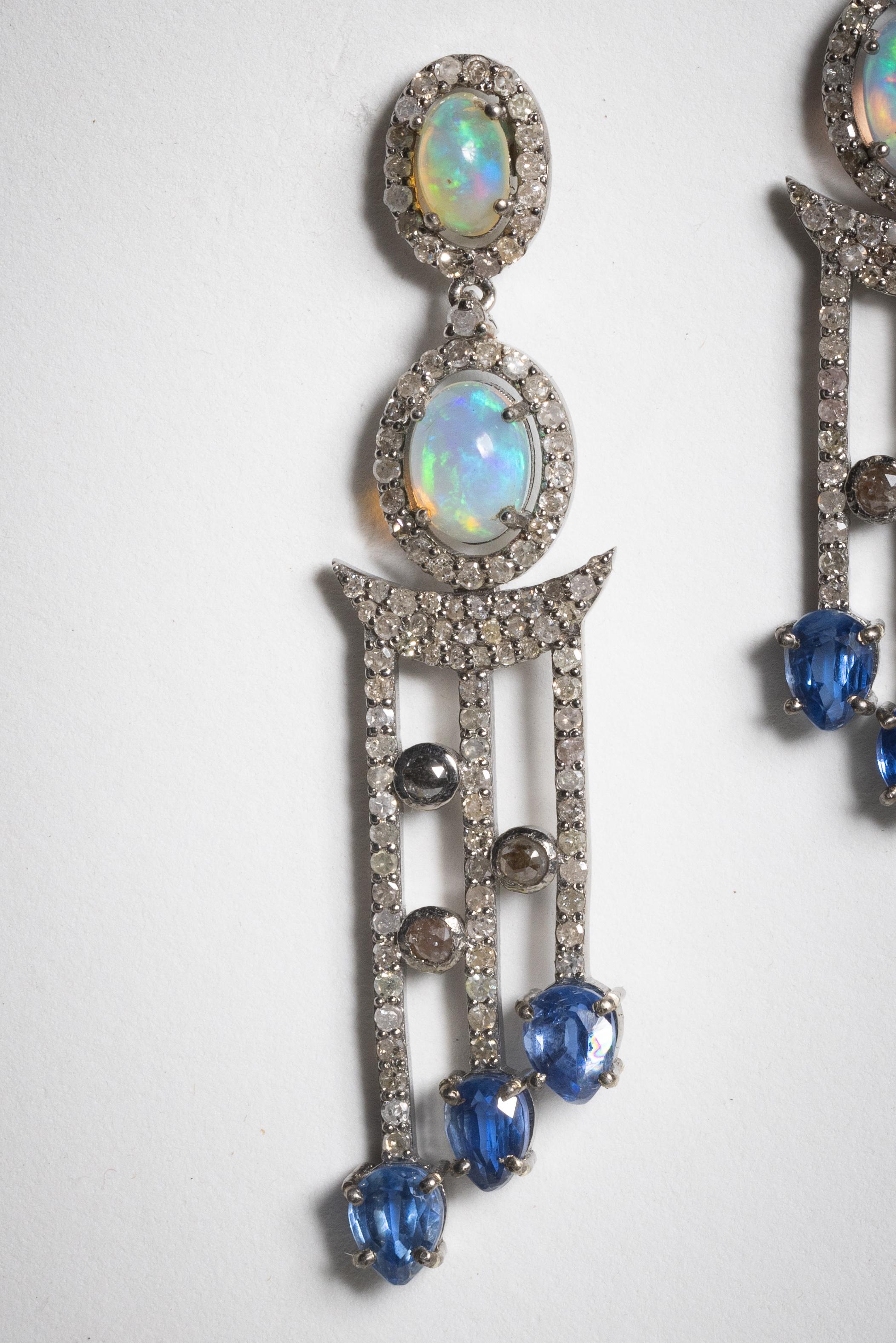 A stunning pair of dangle earrings, almost with a motif of musical notes on a scale.  Features include oval shaped opals with faceted, oval Kyanite gemstones at the bottom and a multitude of round, brilliant cut diamonds throughout and bordering the