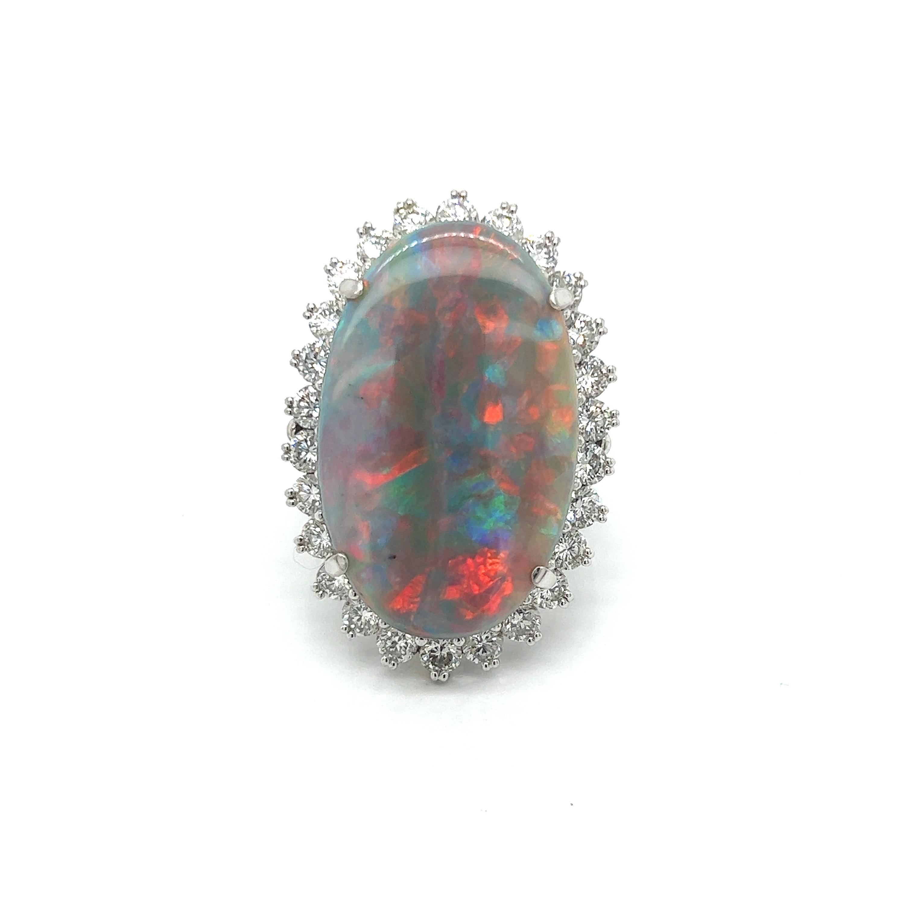 This exquisite ring features a large 15.28 carat cabochon oval opal. The opal is surrounded by A halo of twenty six round diamonds totaling 2.61 ctw, The diamonds are VS2-SI1 in clarity and H-I in color.  Mounted in platinum.  Total weight is 23.86