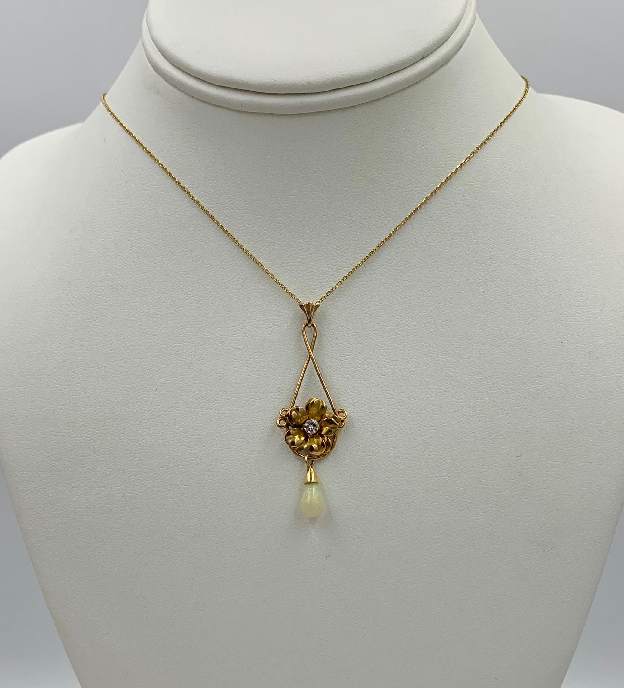 AN ART NOUVEAU PENDANT IN THE FORM OF A FLOWER SET WITH A SPARKLING ROUND DIAMOND IN THE CENTER OF THE FLOWER WITH A PEAR SHAPED OPAL HANGING PENDANT ALL IN 14 KARAT GOLD. THE  WONDERFUL THREE DIMENSIONAL DEPICTION OF THE FLOWER, WHICH MAY BE A