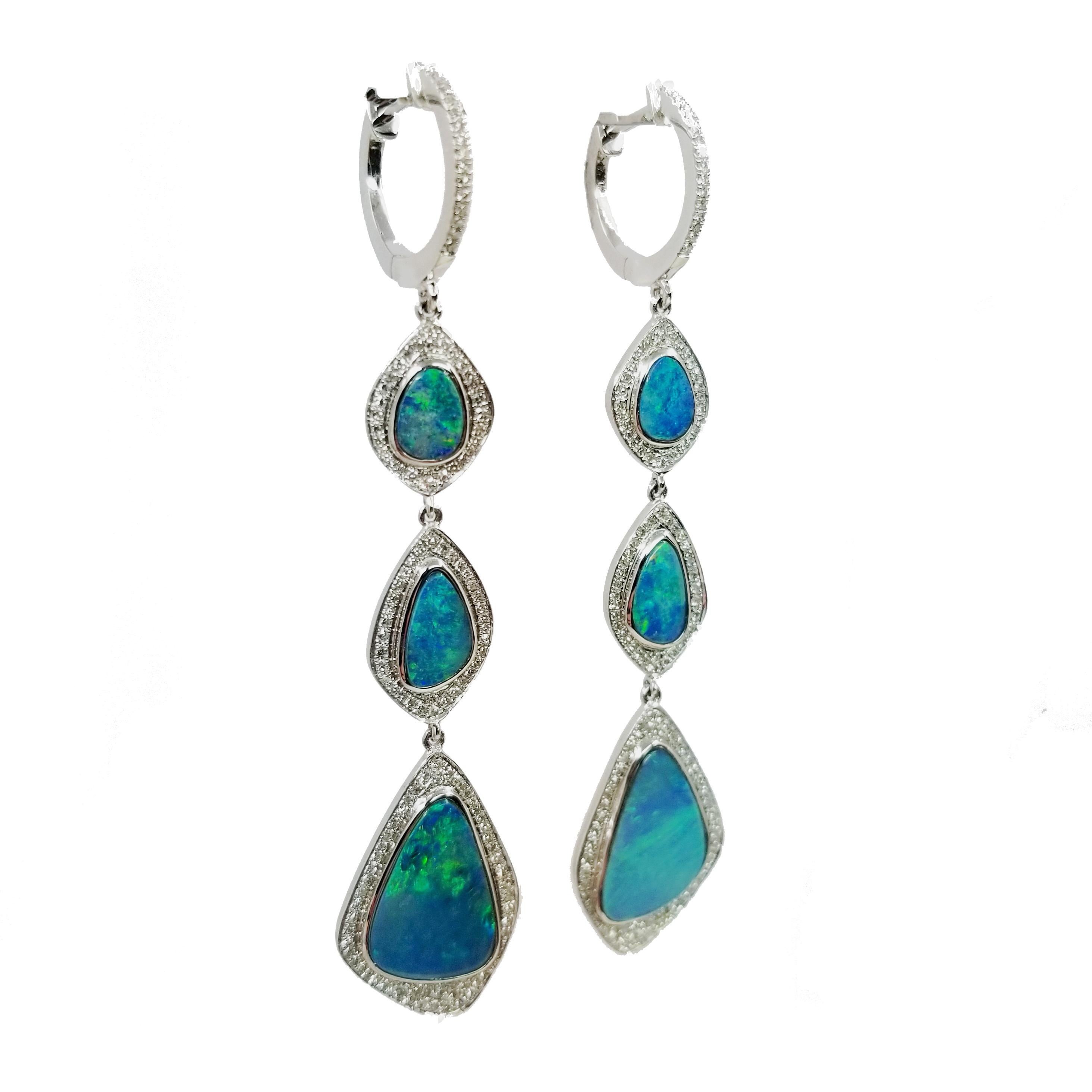 One of a kind opal earrings hand crafted in 14 karat white gold. The drop earrings feature 6 bezel-set opals totaling 3.96 Carats & 266 Round Diamonds totaling 0.64 Carats. The top is a mini hinged hoop attachment, with click closure. Total length