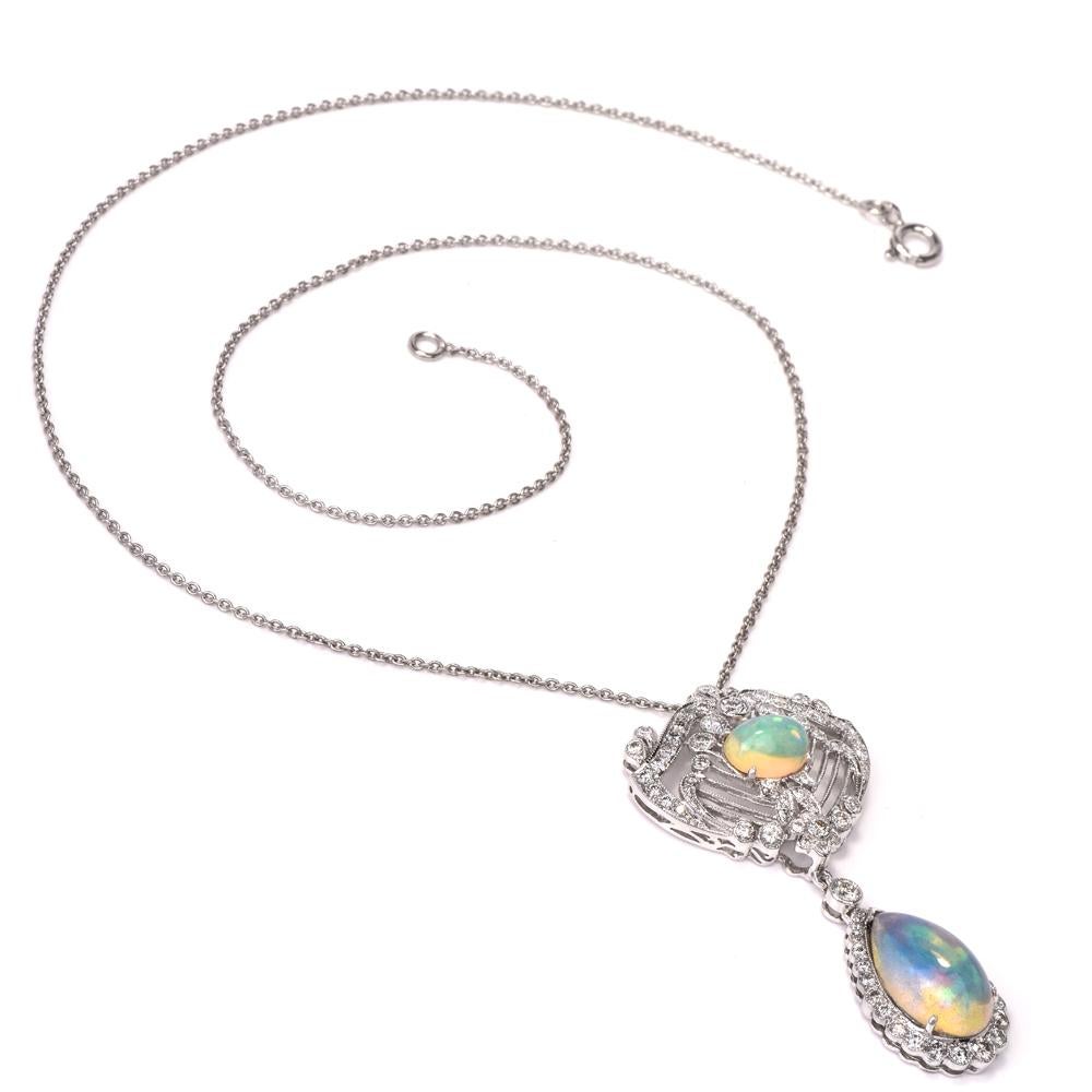 This estate opal and diamond pendant necklace is crafted in 18K white gold. Displaying two prominent opals approx. 3.20cts, bigger lower opal dangles. Pendant features an interact floral open work design covered in round-cut diamonds approx.