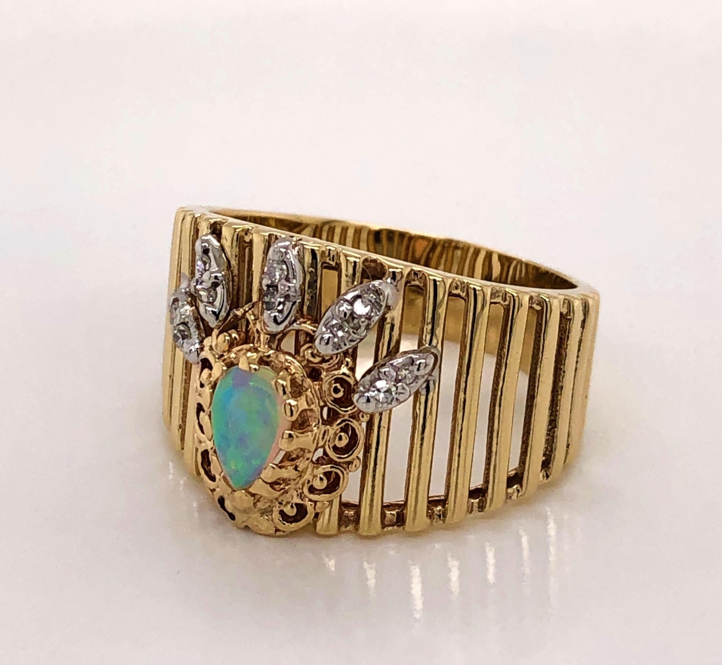 Crown your hand with this stunning pear shaped opal and diamond gold ring. Vertical filigree in fourteen karat (14k) yellow gold graduate to the face of the ring to showcase the special effect of this phenomenal color changing opal gem.  Diamond