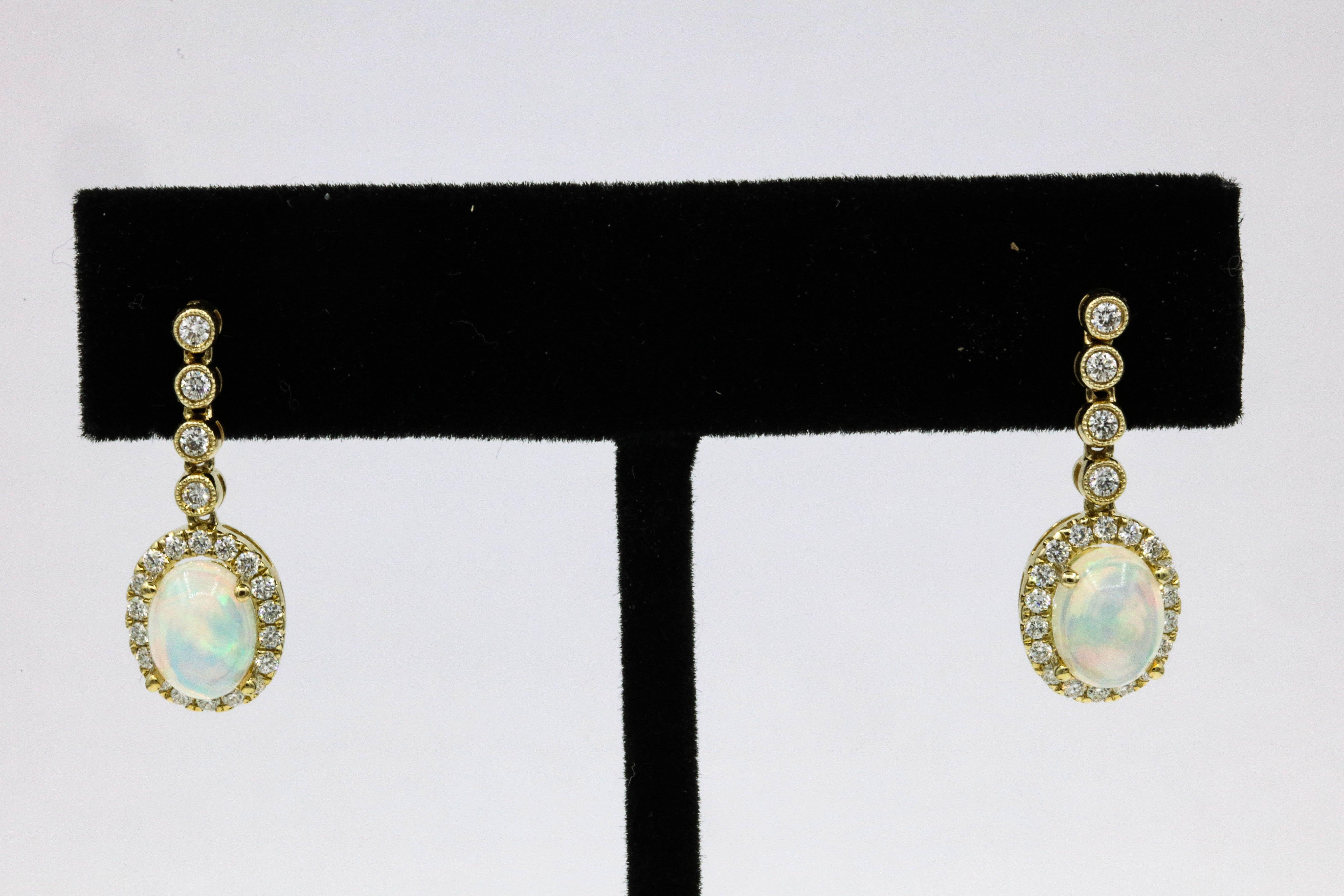 14k Yellow gold drop earrings featuring two Ethiopian Opals, 1.78 carats surrounded by round brilliants weighing 0.54 carats. 
Color G-H
Clarity SI