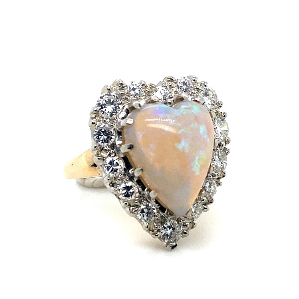 An opal and diamond 14 karat white and yellow gold cluster engagement ring.

This vintage cluster ring is designed as a sweet heart shape 

The centre is set with a lively heart shaped cabochon cut opal and round brilliant cut diamond surrounds for