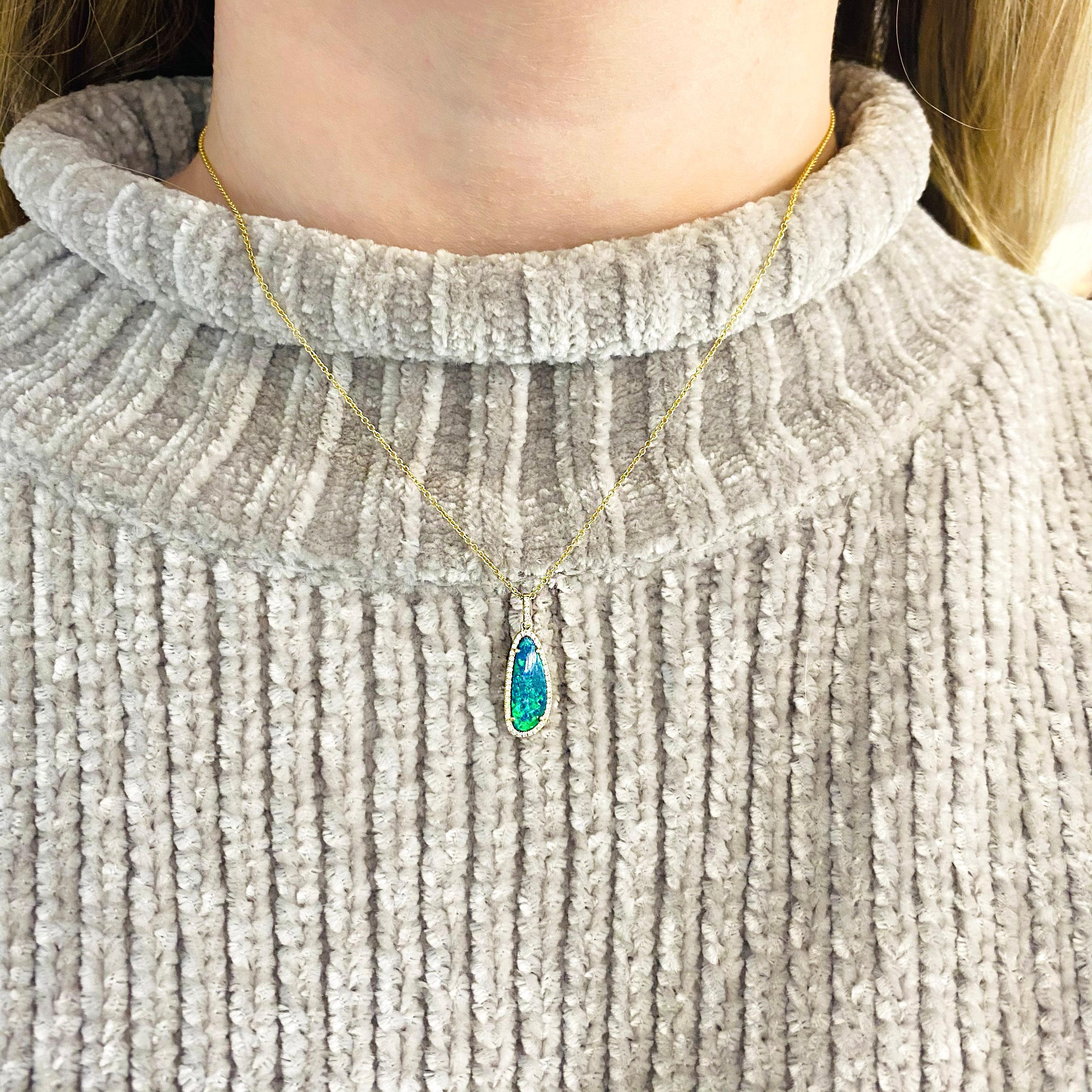 This blue opal pendant has a halo of diamonds around it and is set in a beautiful lush 14 karat gold yellow gold cable chain. This is an amazing bright blue pendant and looks great when layered with other necklaces. Our jeweler makes this pendant
