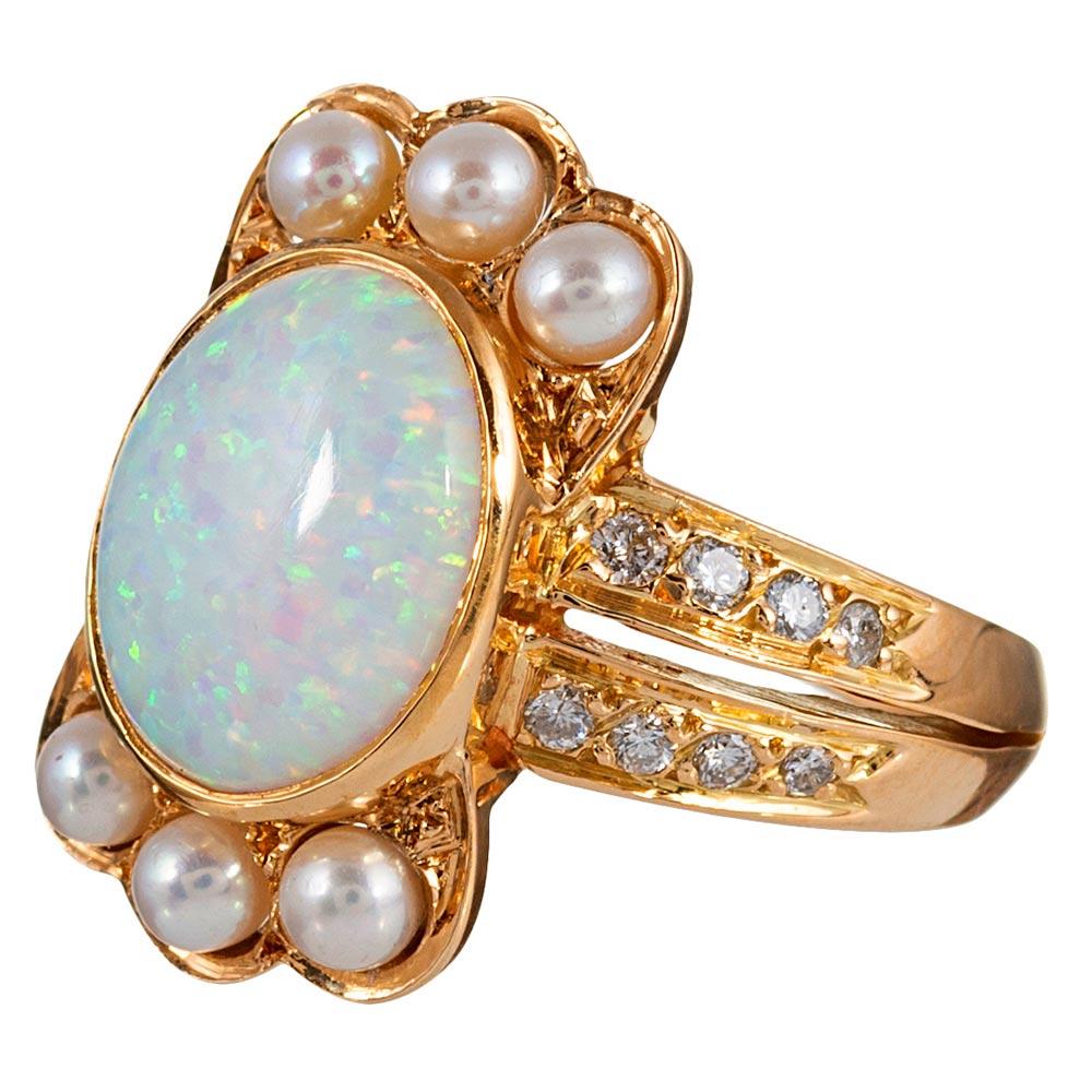 A trio of lustrous pearls flanks each side of a bezel-set cabochon of opal, with brilliant white diamonds (.25 carats in total) cascading down the split shank. It appears the pearls form a crown atop the oval cabochon! The opal weighs 4 carats and