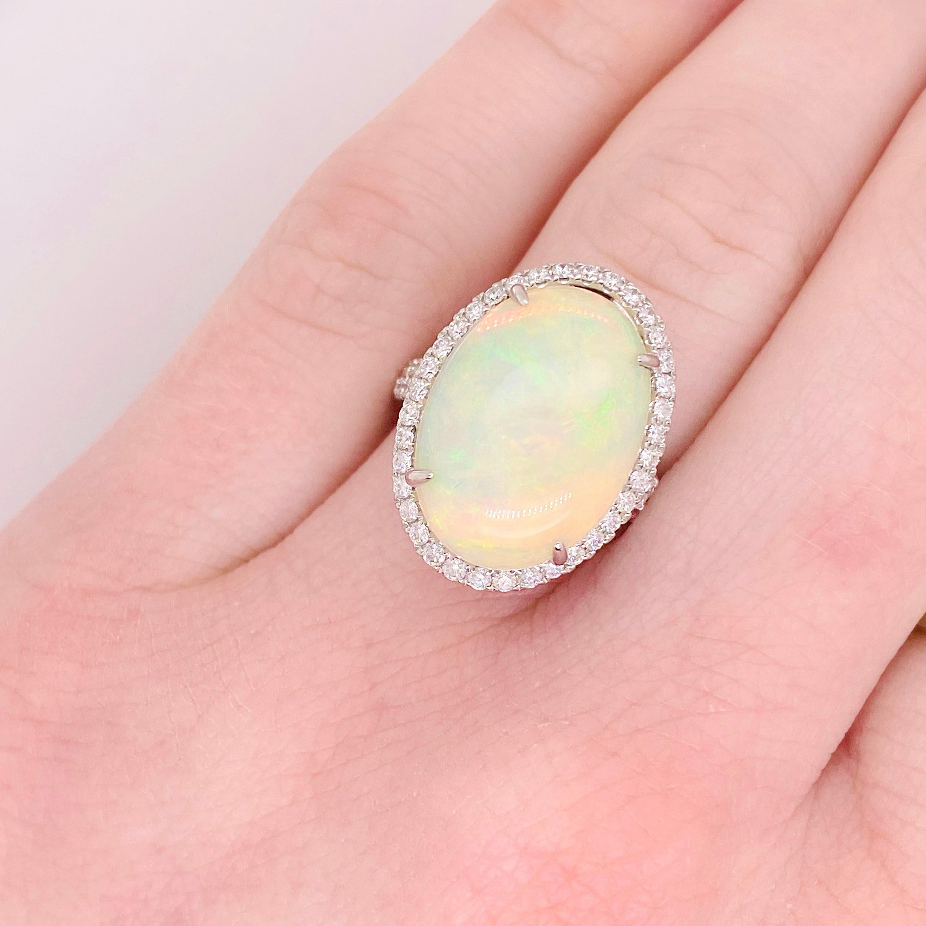 This fiery 7.13 carat opal has flashes of blue, green, and vibrant pink and there are 74 diamonds to frame its beauty. The colors look even more intense in the center of a stunning white diamond halo. More diamonds fall down the split band with one