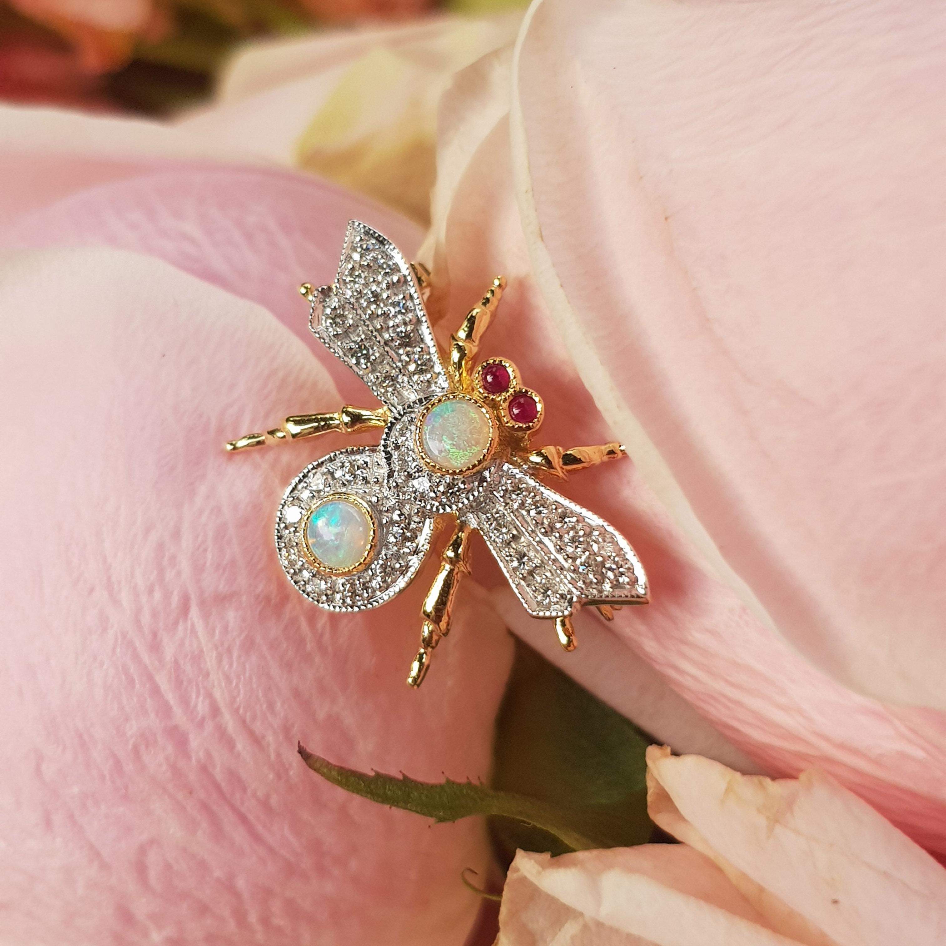 A diamond bee brooch, in the form of a bumble bee in flight, the delicately flying wings, domed body and stretched legs encrusted with two opal on its body, round cut diamonds, with ruby eyes, all set in 18k gold mounting. This gorgeous, glittering