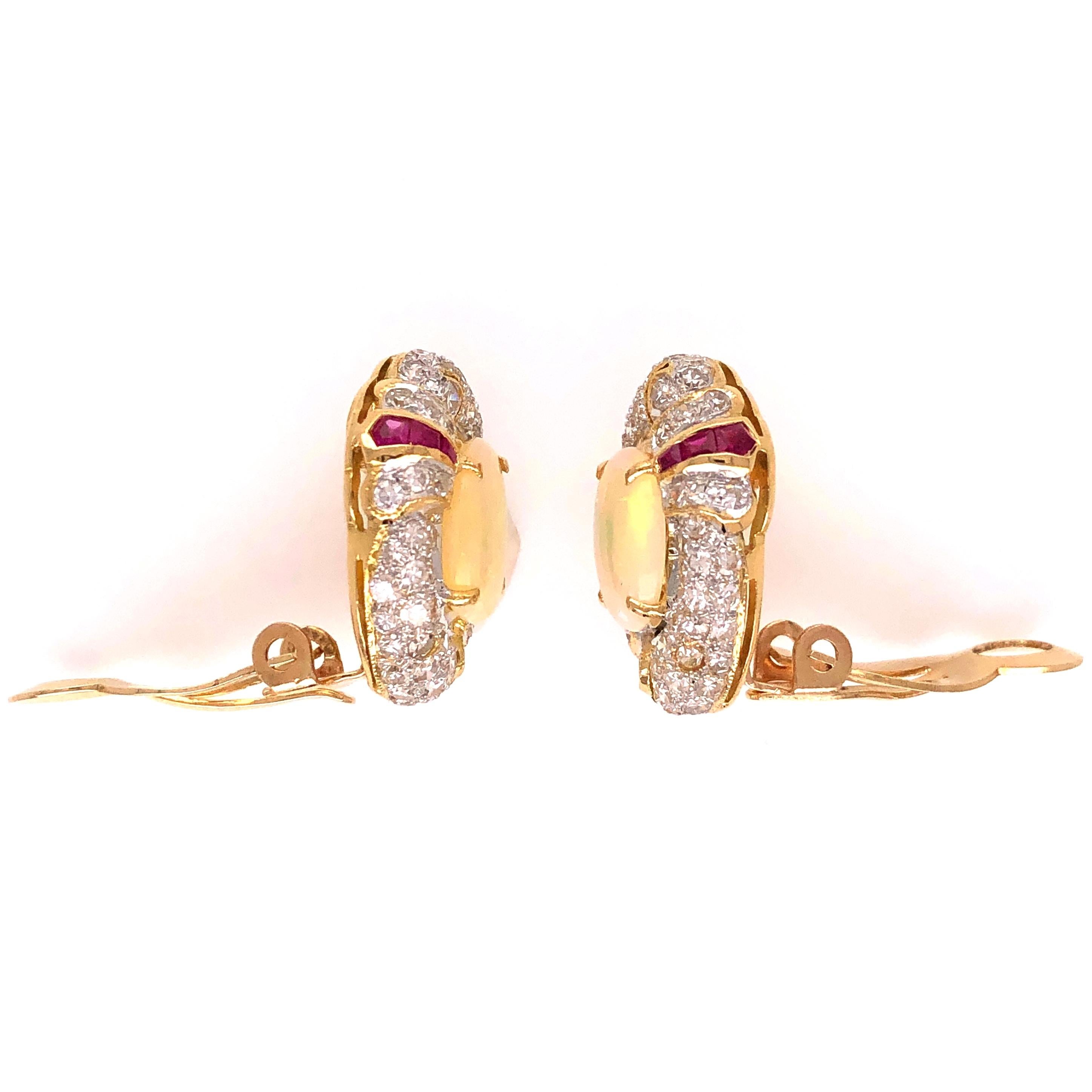 Simply Beautiful Opal Diamond Ruby French Clip Earrings. Center of each earring securely set with a White Opal, weighing 2.00tcw for the 2 opals, surrounded by Diamonds, approx. 1.75tcw and enhanced with Rubies. Hand crafted 18K Yellow Gold setting.