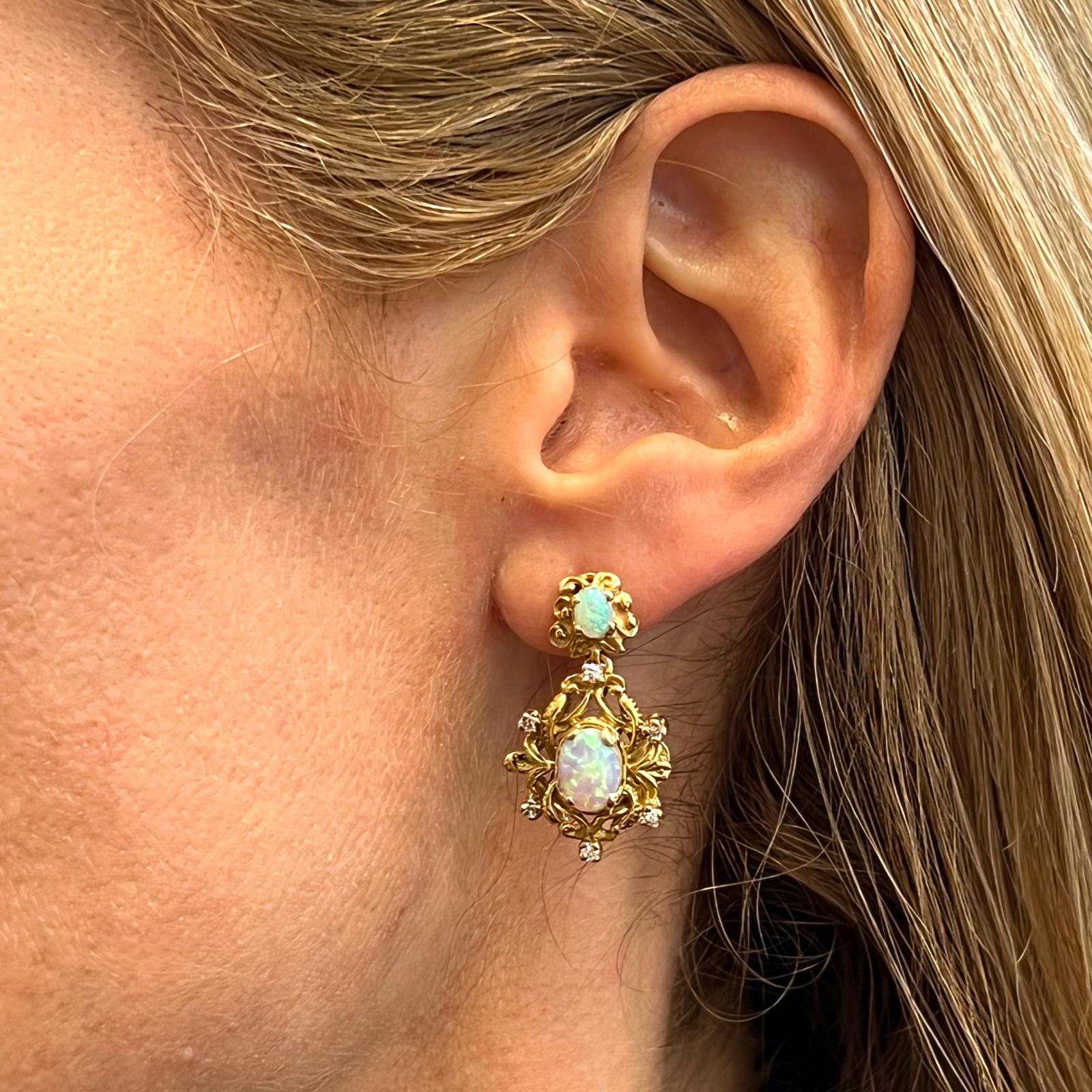 Opal diamond drop earrings crafted in 14 karat yellow gold. The earrings feature 4 colorful opal gemstones and 12 round brilliant cut diamonds weighing .25 carat total weight. The diamonds are graded H-I color and SI clarity. The earrings are