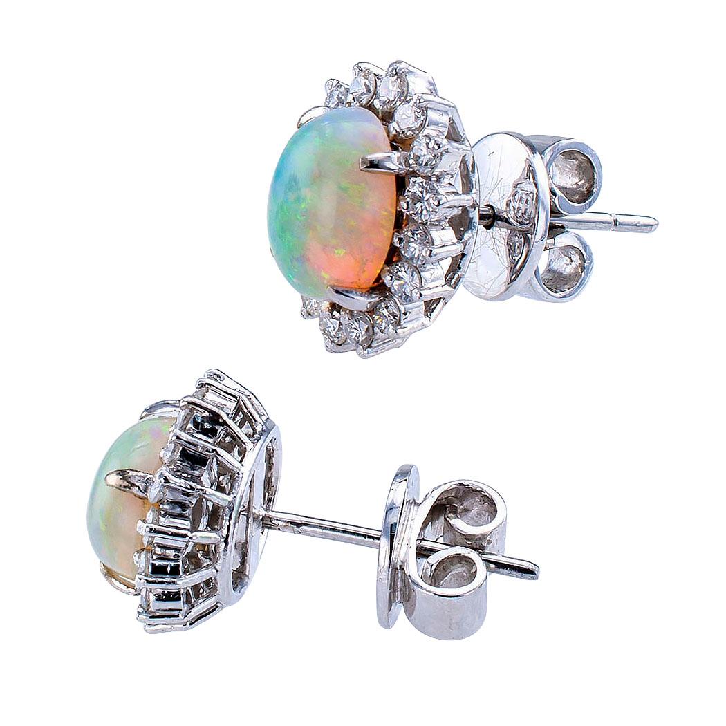 Opal and diamond white gold earring studs circa 1960. Showcasing a pair of oval-shaped opals within conforming borders set with round brilliant-cut diamonds totaling approximately 0.80 carat, approximately H – I color and VS clarity, mounted in