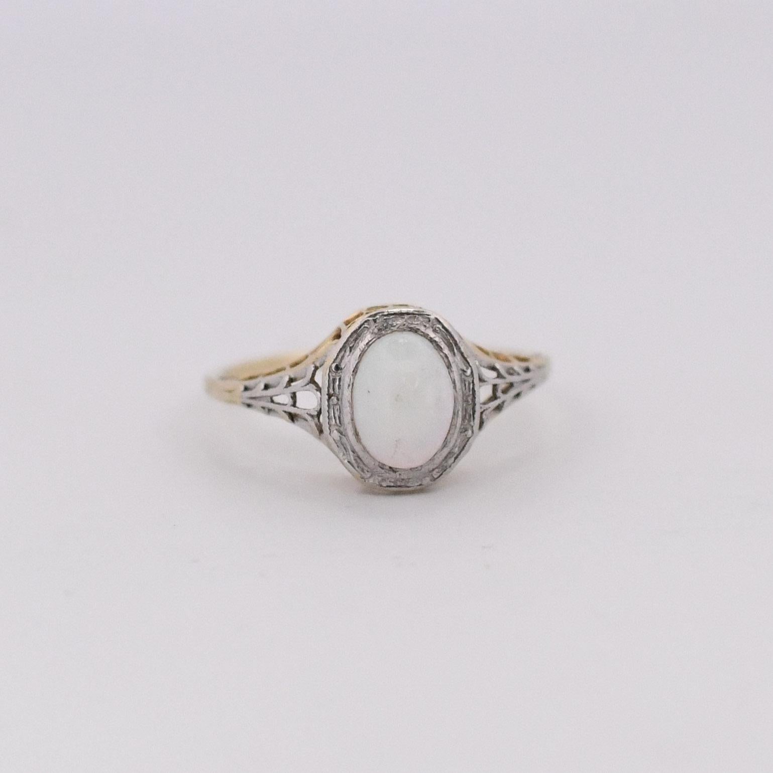 This exquisite ring features a mesmerizing opal, embraced by a setting crafted from 14k yellow gold with a Platinum Top. The delicate filigree detailing on the band adds a touch of vintage elegance, showcasing a harmonious blend of precious metals.