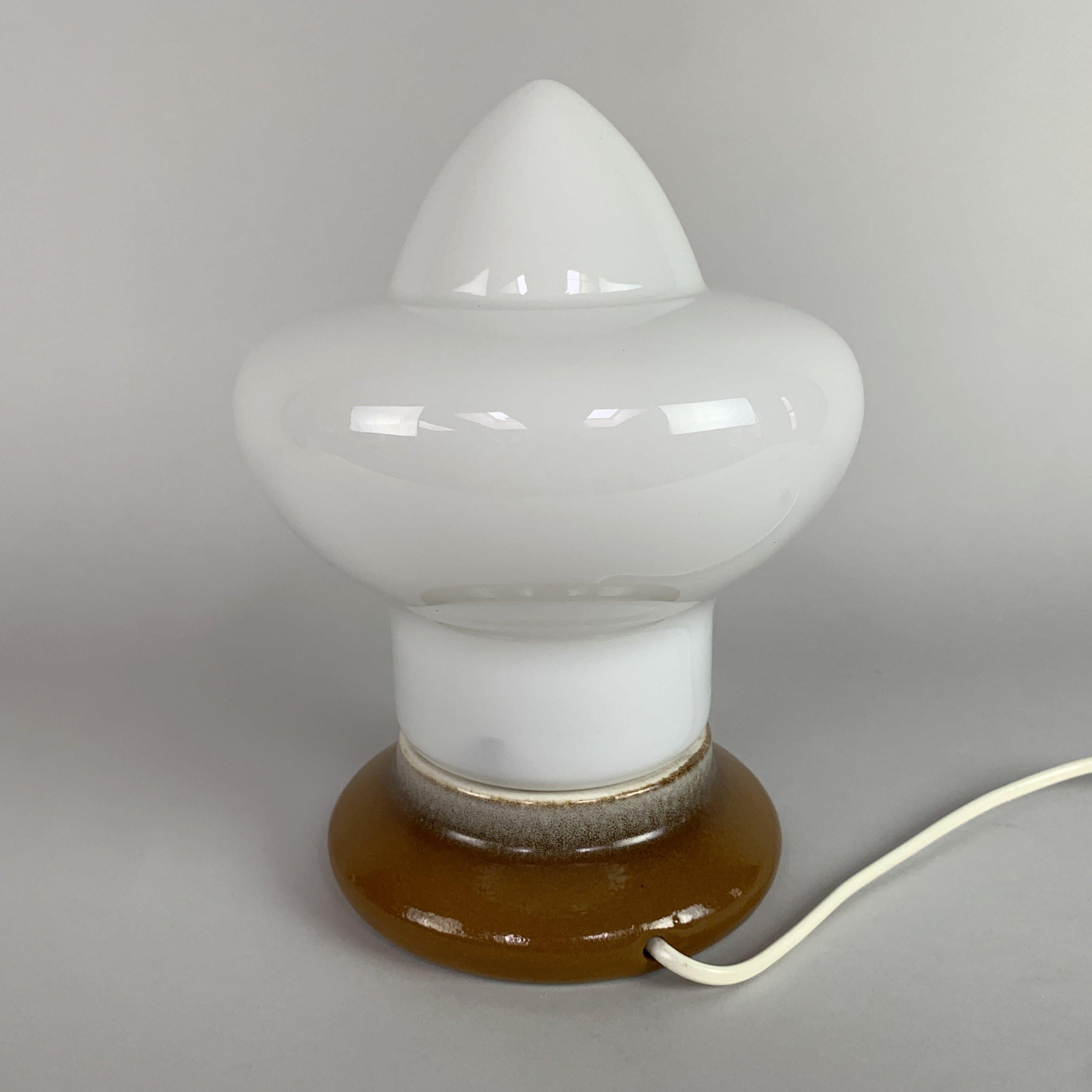 Questa lampada da tavolo vintage unica nel suo genere catturerà l'attenzione di chiunque, sia che sia accesa o meno. Realizzato in vetro opalino con fondo in ceramica smaltata. Progettato da Ivan Jakes per Osvetlovaci Sklo a Valasske Mezirici