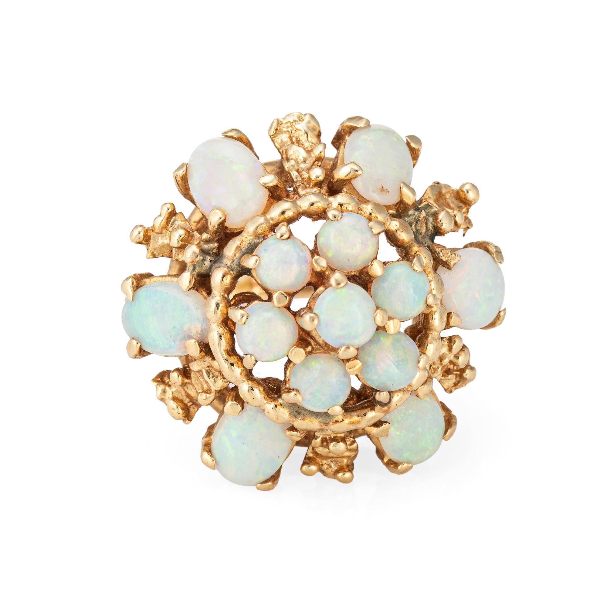 Stylish vintage opal harem cocktail ring crafted in 14 karat yellow gold (circa 1960s to 1970s). 

13 opals range in size from 6mm x 4mm to 2.5mm.

The natural opals show green to purple, orange, yellow and bits of red color flashes. Set into a high