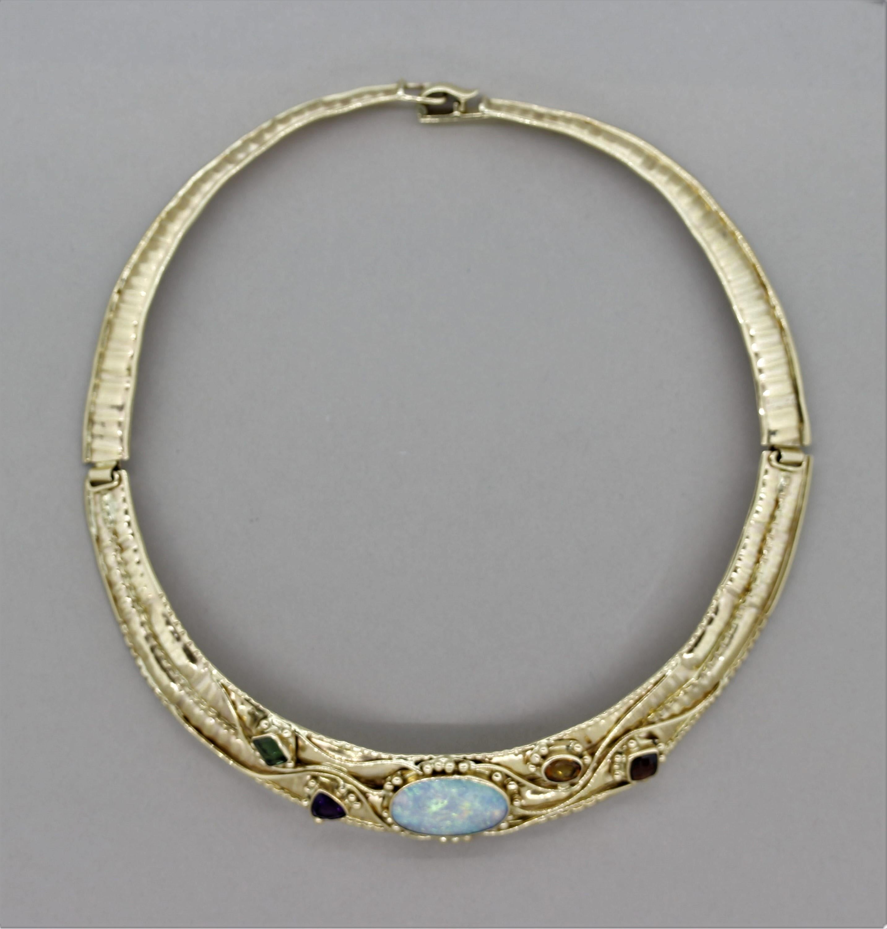 A unique hand-fabricated collar necklace featuring a beautiful Australian opal in the center. It is accented by 4 other gemstones, a green tourmaline, purple amethyst, orange citrine and red garnet, which together adds color and brilliance to the