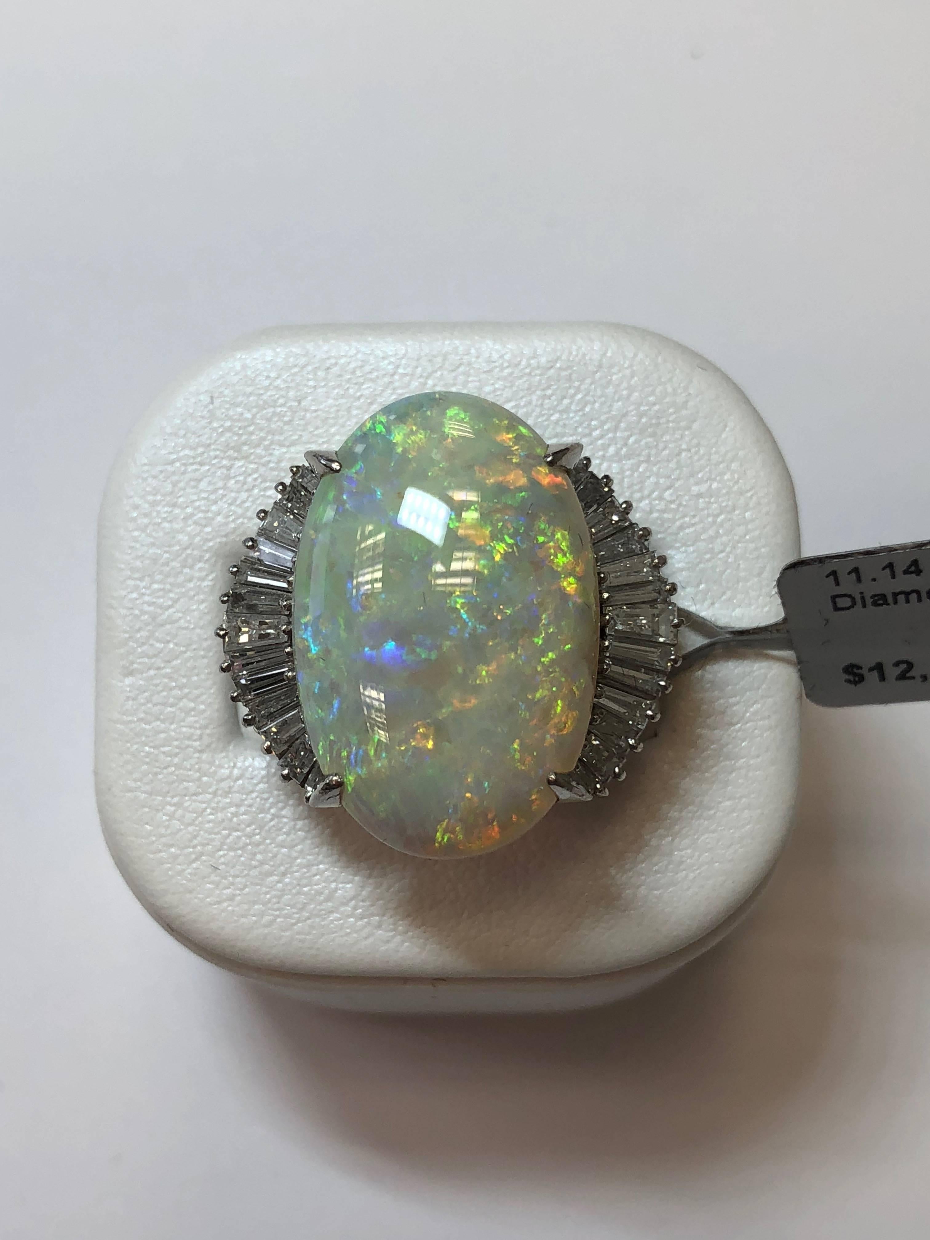 Gorgeous cocktail ring showcasing 11.14 carat opal oval with 1.33 carats of white diamond baguettes in a platinum mounting size 5.75.  This ring will be amazing for any occasion and a great addition to any collection.