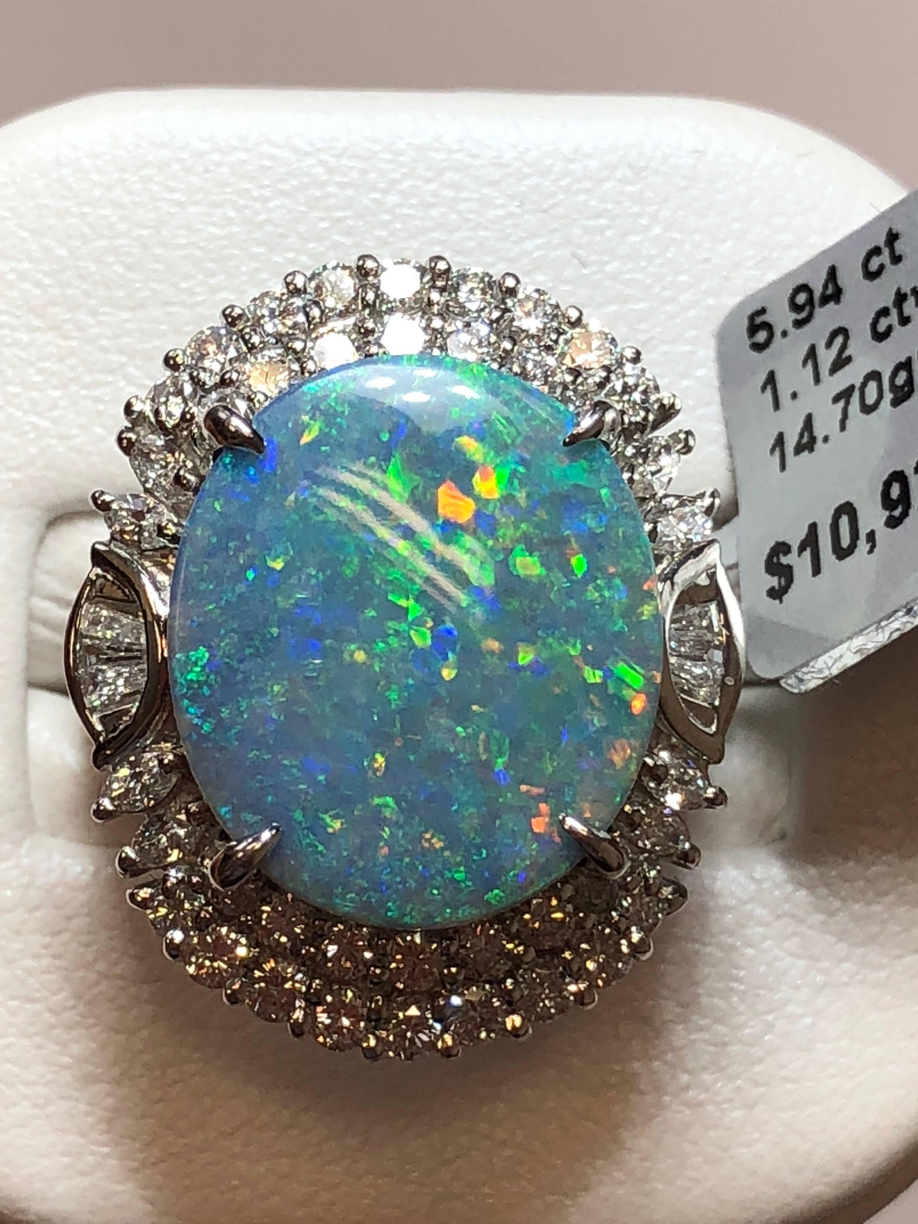 Exquisite 5.94 carat opal oval cabochon surrounded by 1.12 carats of brilliant white diamonds in platinum.  This cocktail ring is a showstopper with vibrant colors.  It is a size 5.25.  Perfect to add to your jewelry collection!