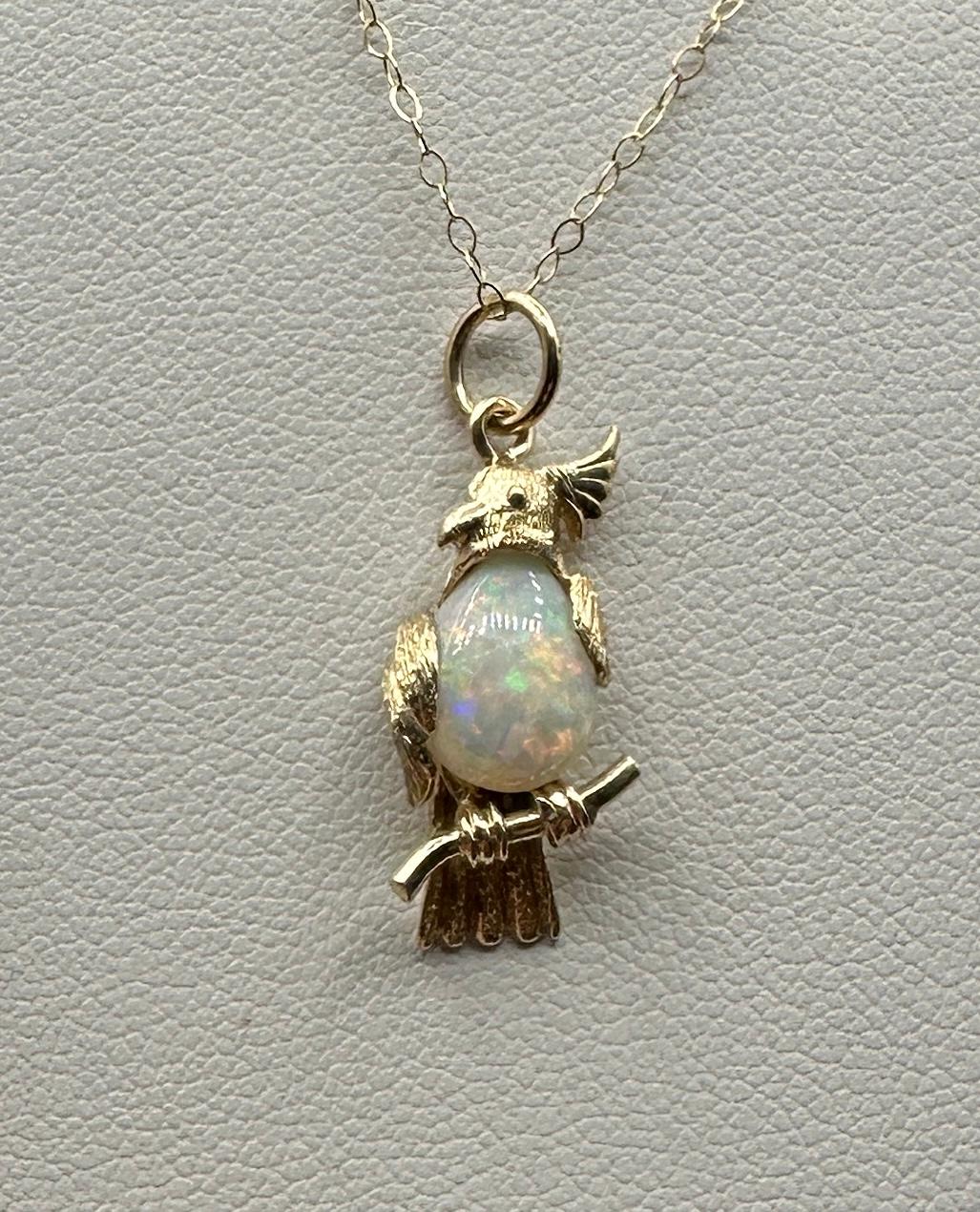 This is a wonderful pendant or charm with a fabulous Parrot or Cockatoo Bird sitting on its perch with a gorgeous pear shape fire opal body.  The pendant is 14 Karat yellow gold.  The radiant pear shape opal is full of fire with blue, green, orange,