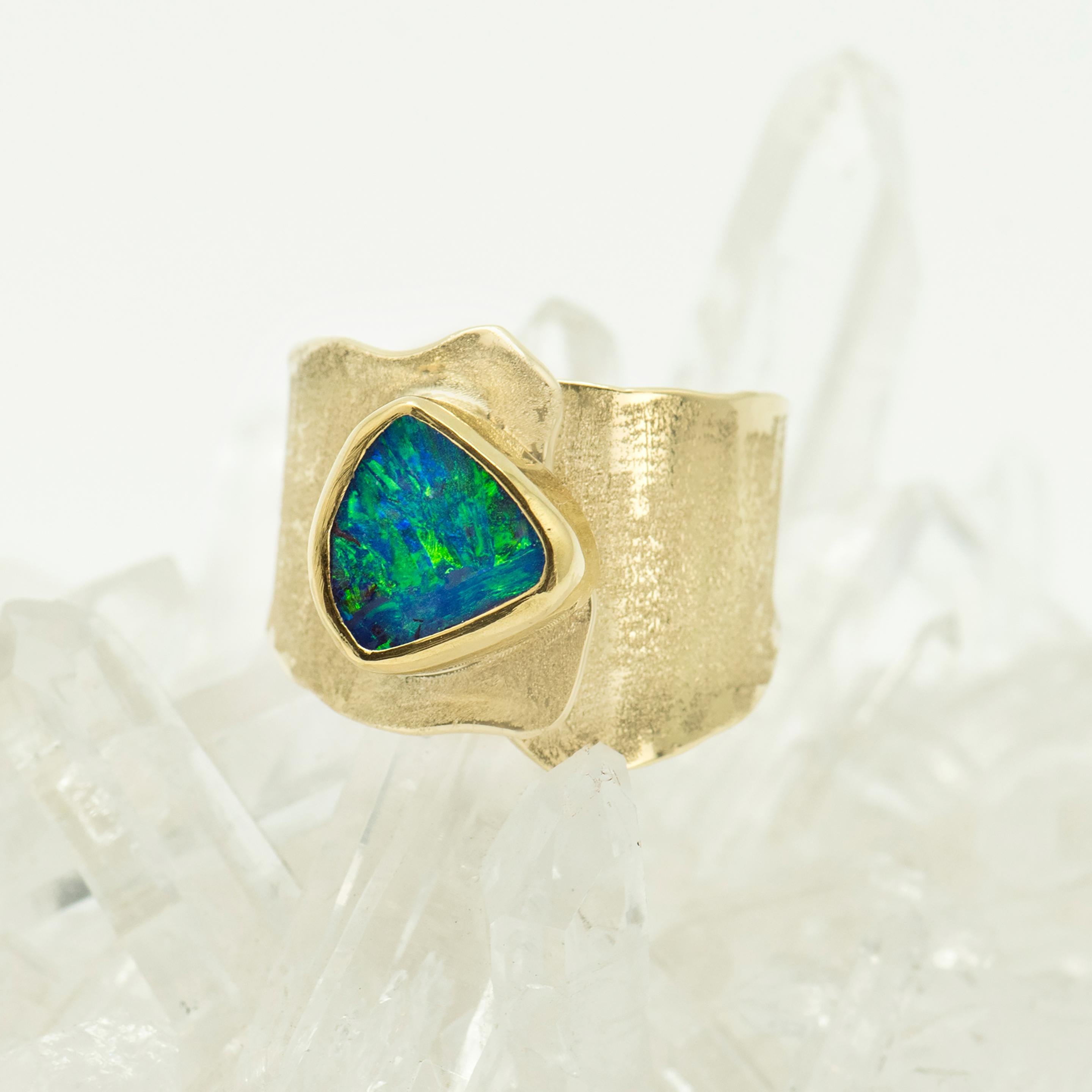 Boulder opal is one of the most beautiful gems on earth.  Its variety is unequal, thus each opal is unique unto itself.  That is special.  This boulder opal has  beautiful green flash with some blue.  The wide 18k gold band is textured and very