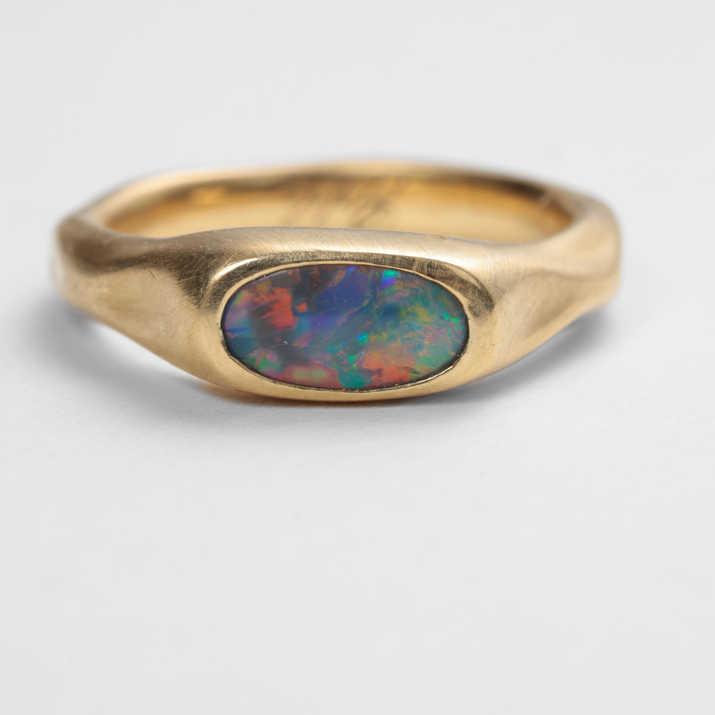 Questo sottile anello in oro giallo 18K fatto a mano, unico nel suo genere, è il veicolo di consegna di uno dei migliori opali neri australiani che abbia mai visto. Misurando circa 8,39 mm x 4,96 x 2,65, non si tratta di un opale enorme, ma il suo
