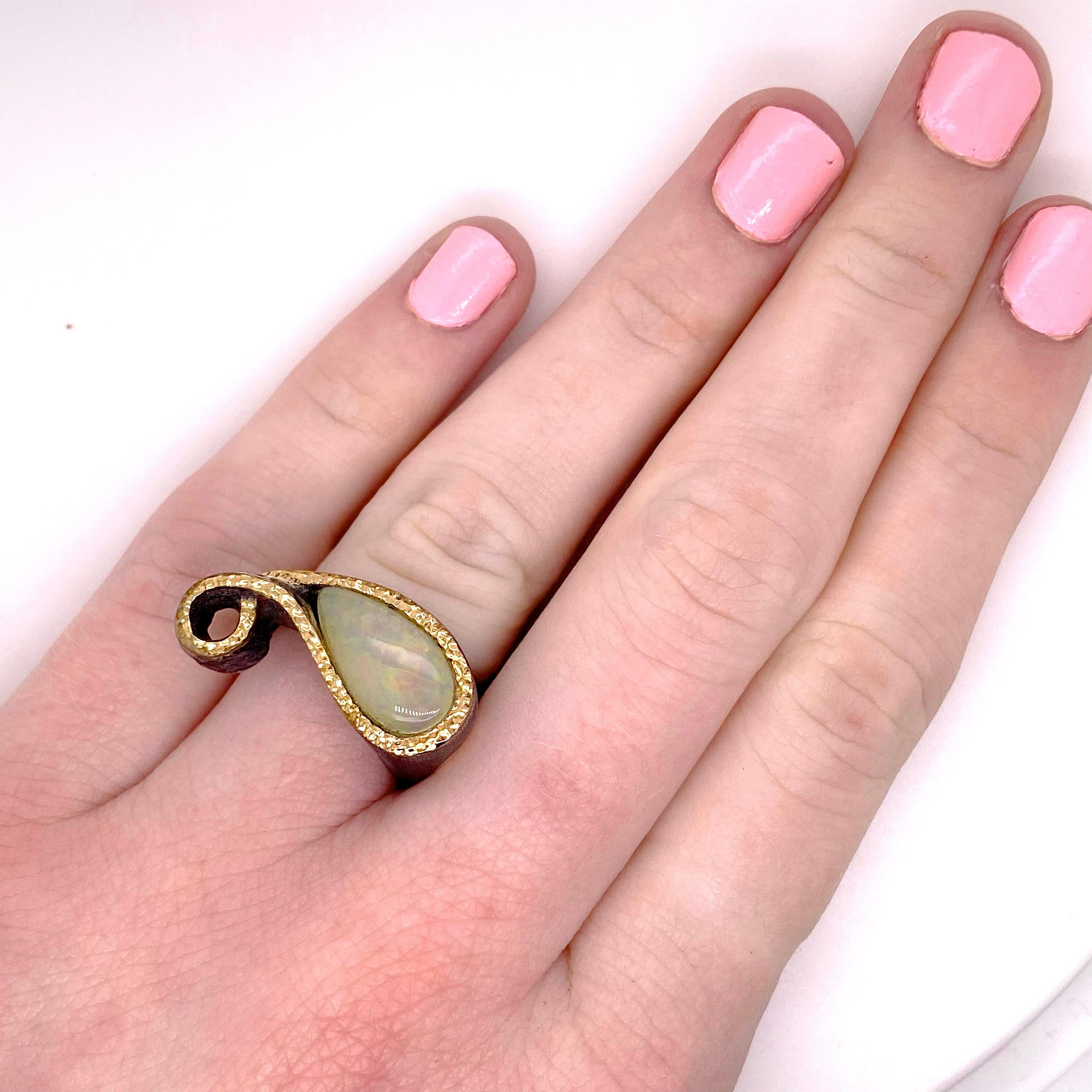 La bague en opale australienne a été fabriquée à la main avec une opale en forme de poire entourée d'une bordure en or. La bague a une forme qui s'adapte parfaitement à vos doigts ! Le dessin comporte deux q bouclés qui forment un adorable motif et