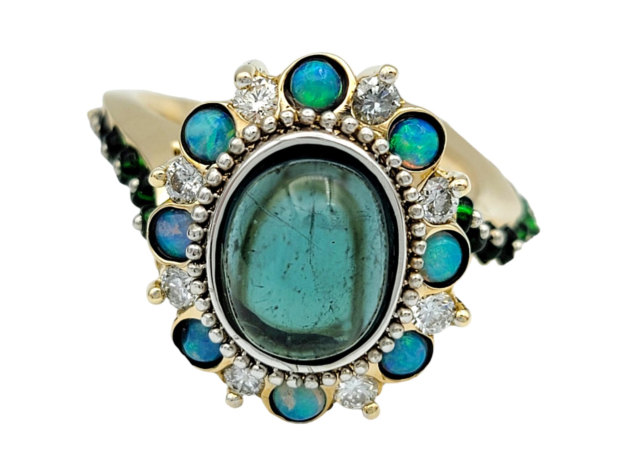Ring Size: 7.75

This stunning multi-stone ring set in 14 karat yellow gold is a breathtaking piece that showcases a harmonious blend of colors and gemstones. At its heart sits a mesmerizing oval cabochon indicolite tourmaline, radiating a deep and