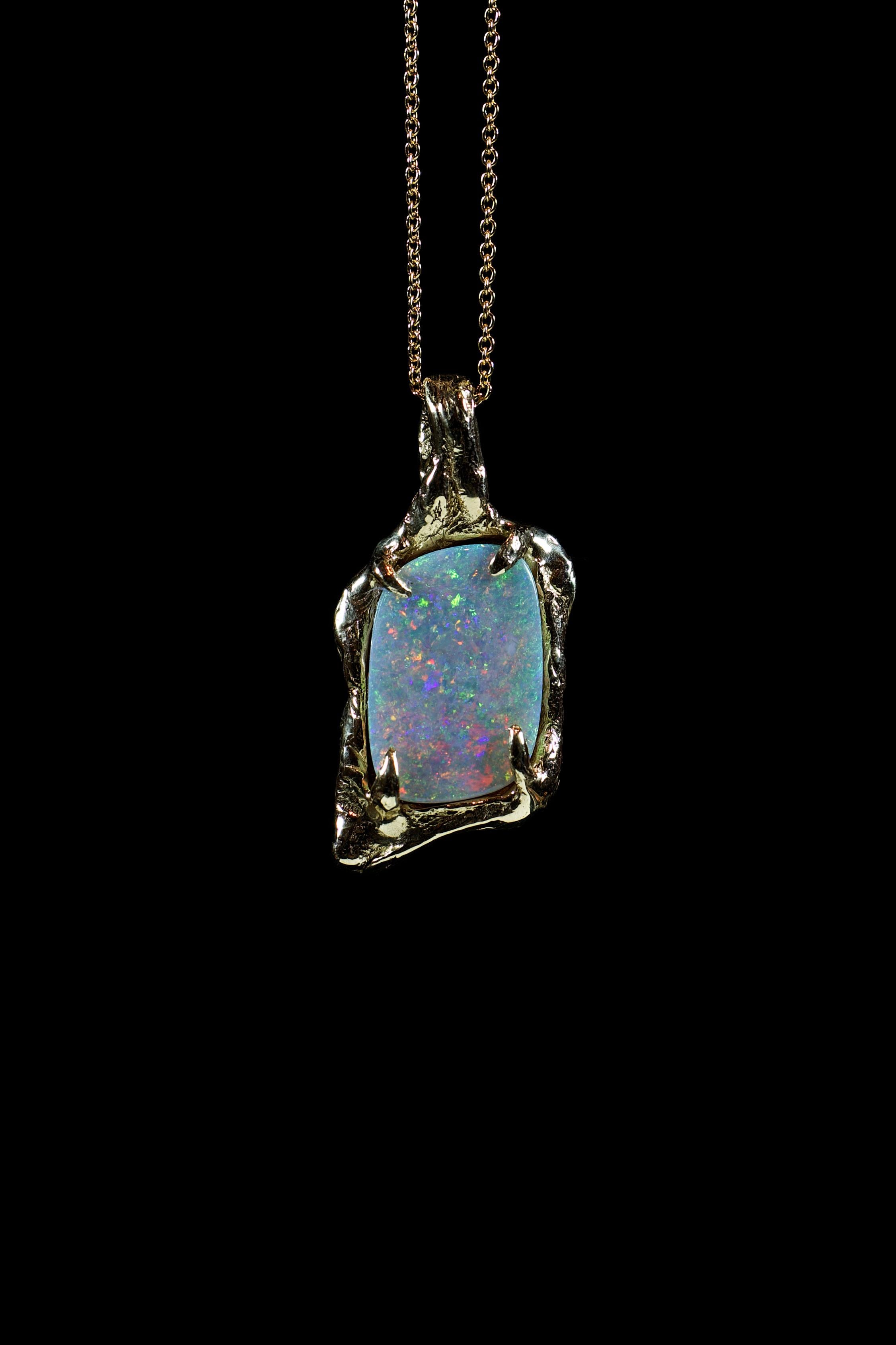 Opal World no. 1 is a breathtaking pendant crafted by Ken Fury from 10K solid yellow gold and adorned with a stunning genuine Australian precious opal. The unique and intricate design of the pendant showcases the opal's incredible play of color,