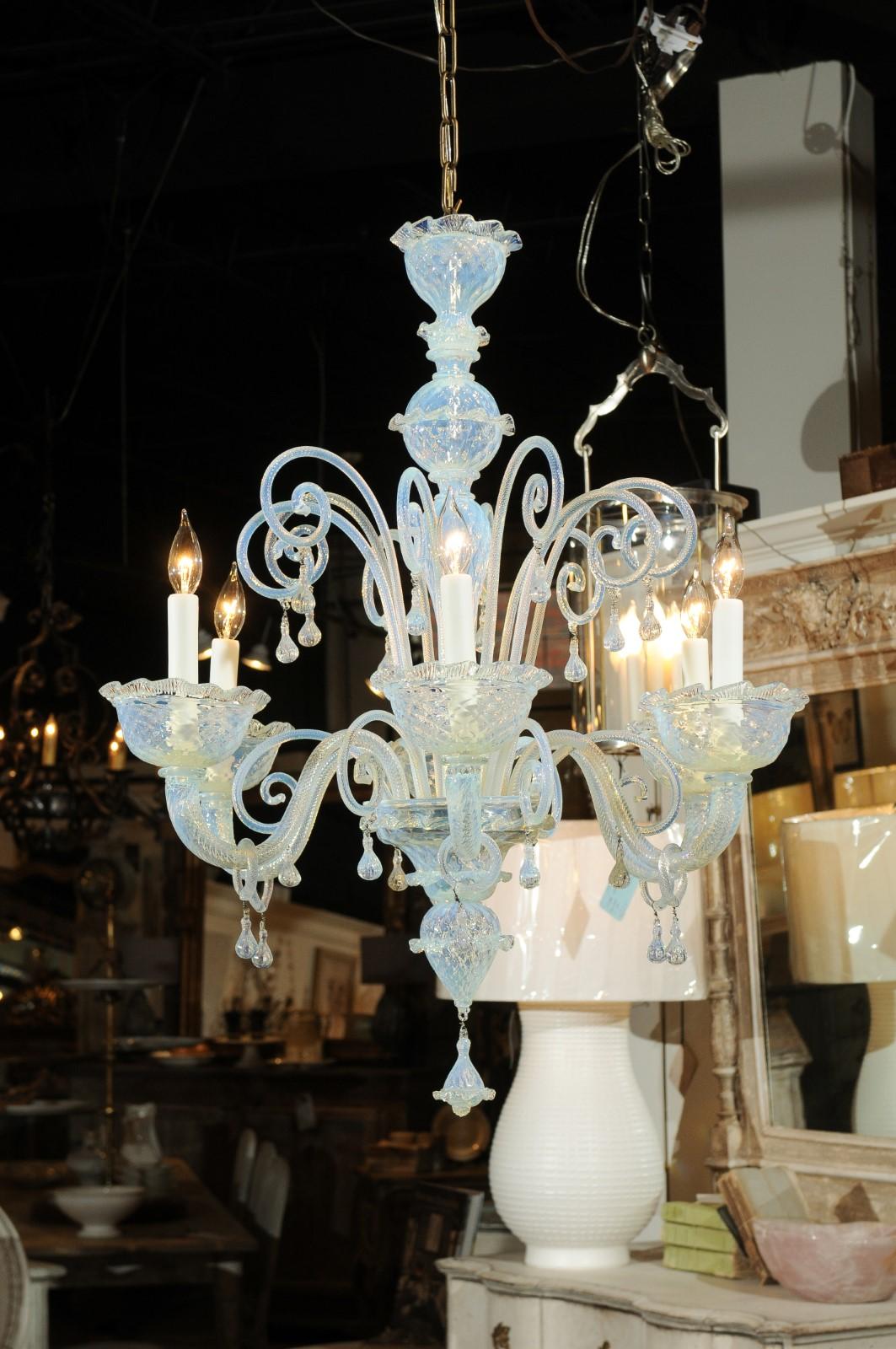 An Italian vintage Murano glass opalene six-light chandelier from the mid-20th century, with scrolling arms and teardrop style motifs. Born in Italy during the midcentury period, this Murano glass chandelier features a central column adorned with