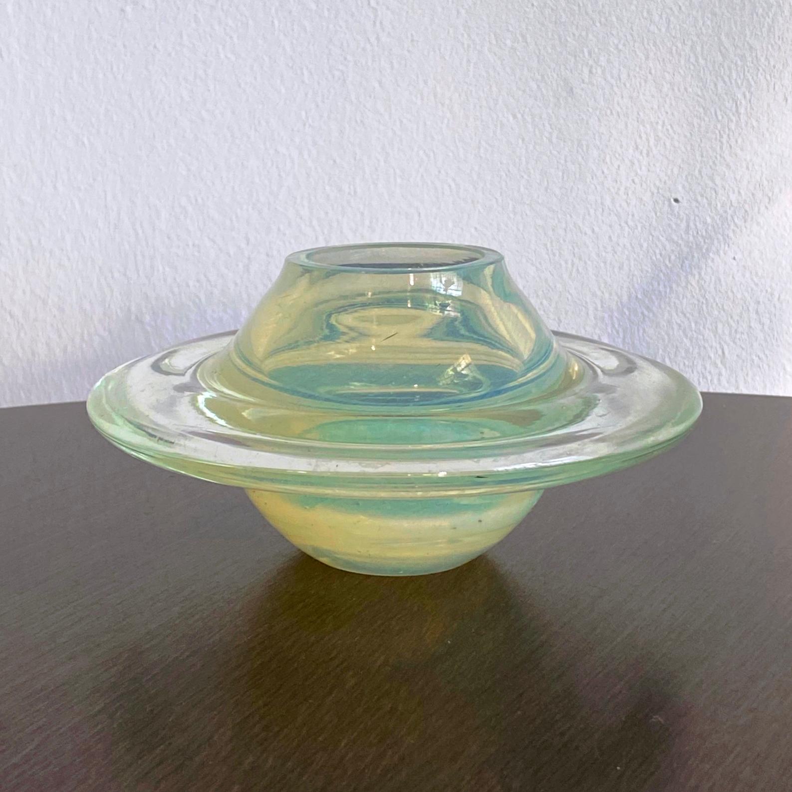 Table or vitrine decoration. Handcrafted, hand-blown Murano glass in the shape of Saturn or flying saucer, space age.
Depending on light source and intensity, the glass color changes from opalescent yellow to greenish. Some marks of use on the