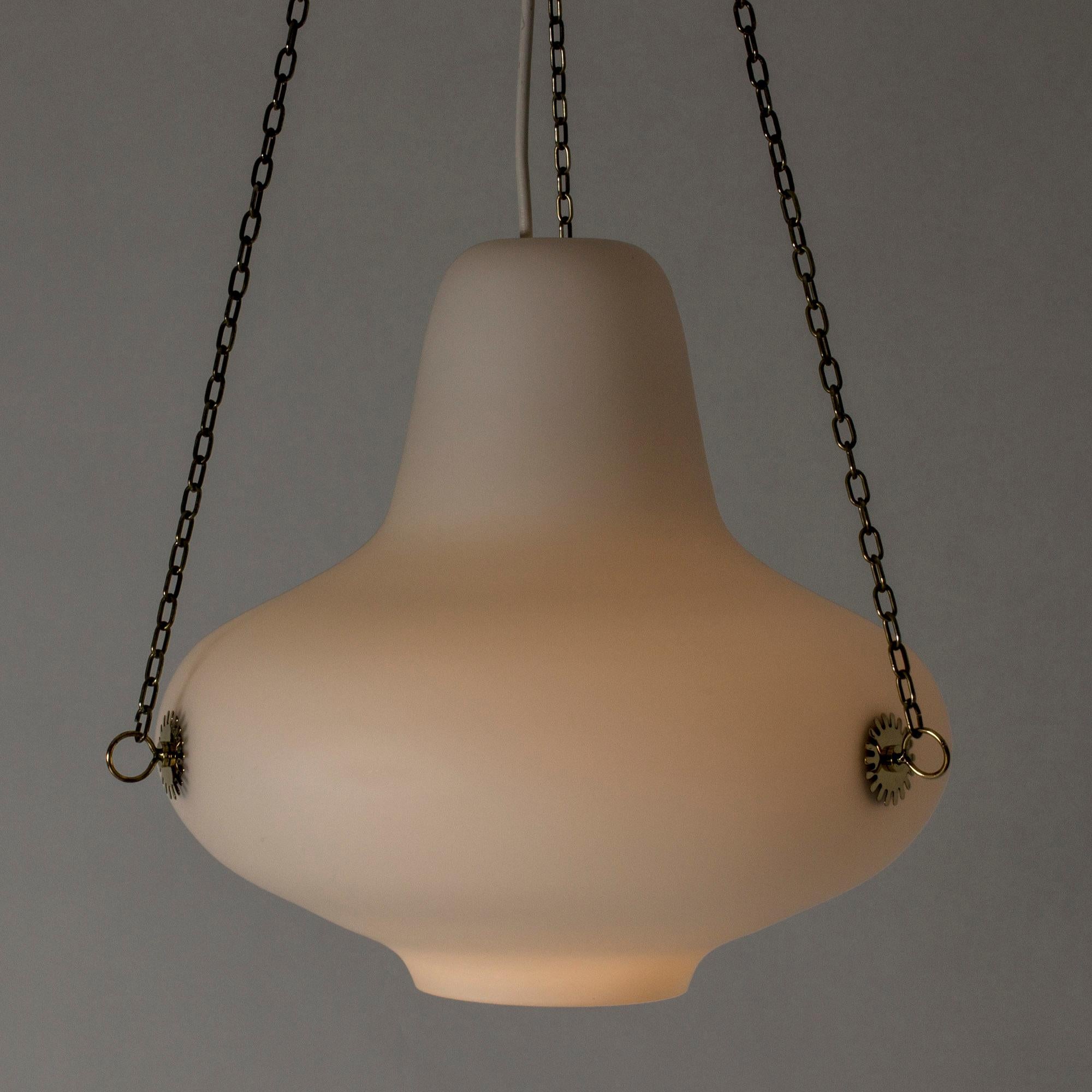 Beautiful ceiling lamp by Carl-Axel Acking, in a bulbous shape, made from opaline glass. Suspended with three brass chains attached to decorative hoops. Simplicity and elegance.