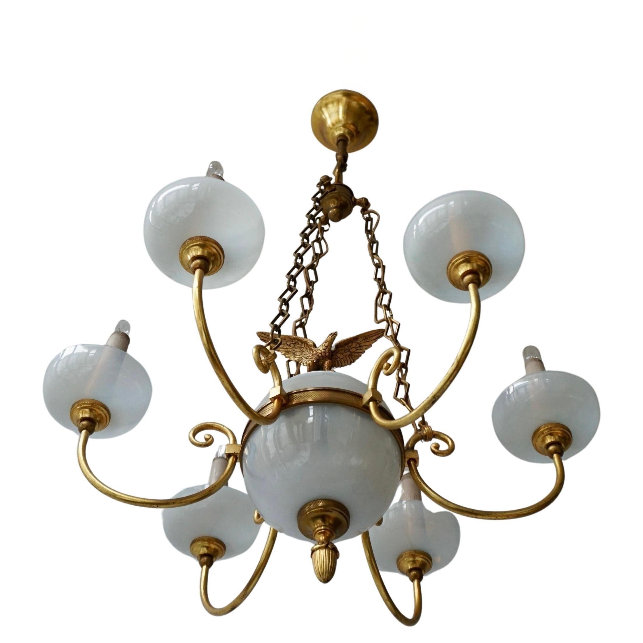 A small chandelier made of brass and opal glass. With six light arms and a central sphere decorated with an eagle.

The chandelier has six sockets for small incandescent lamps with screw base or E14 type LEDs. It is possible to install this fixture