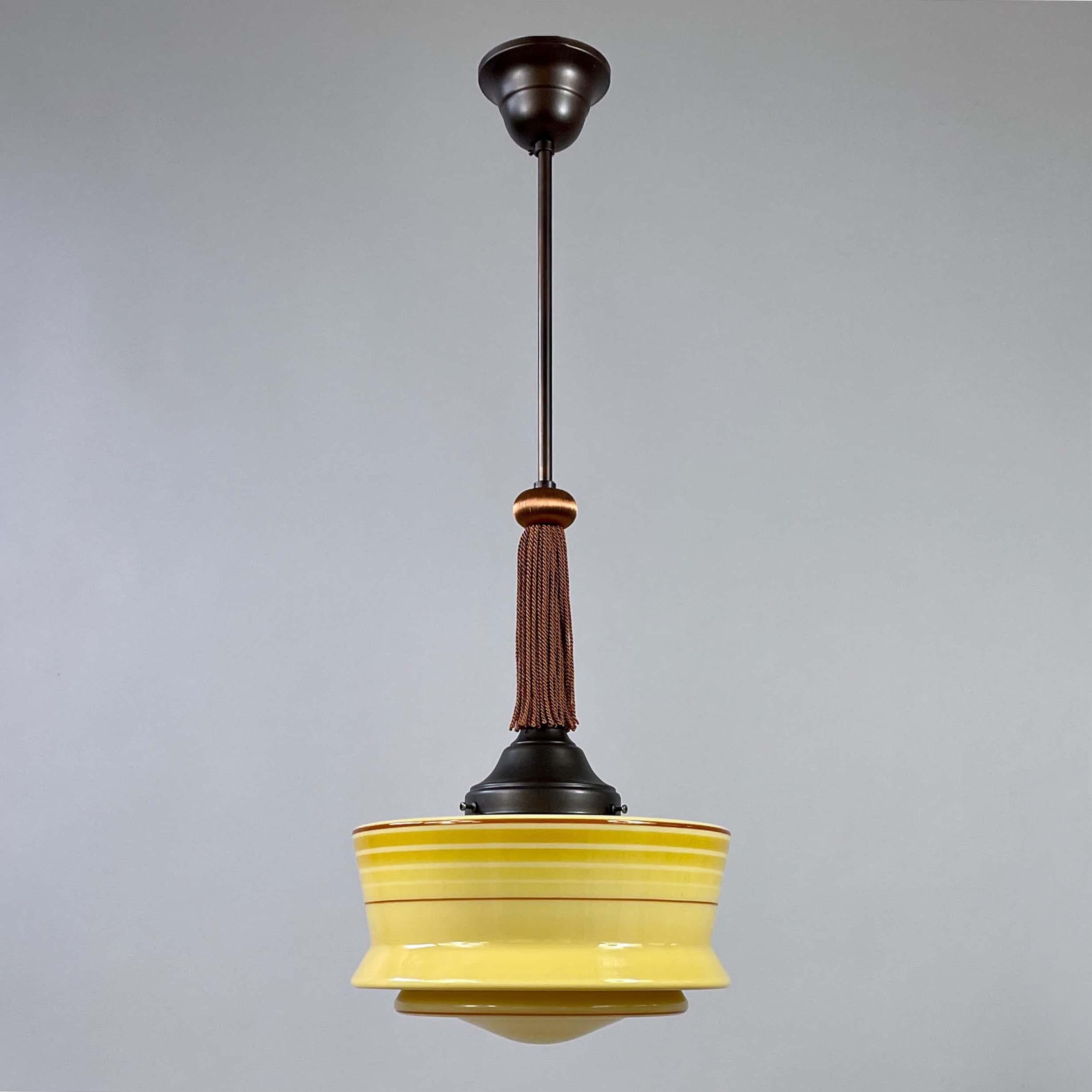 Questo elegante ciondolo Art Déco è stato progettato e prodotto in Germania negli anni '30 durante il movimento Bauhaus.

La lampada è caratterizzata da un paralume in vetro opalino color giallo sabbia con bordi delicatamente svasati e sottili