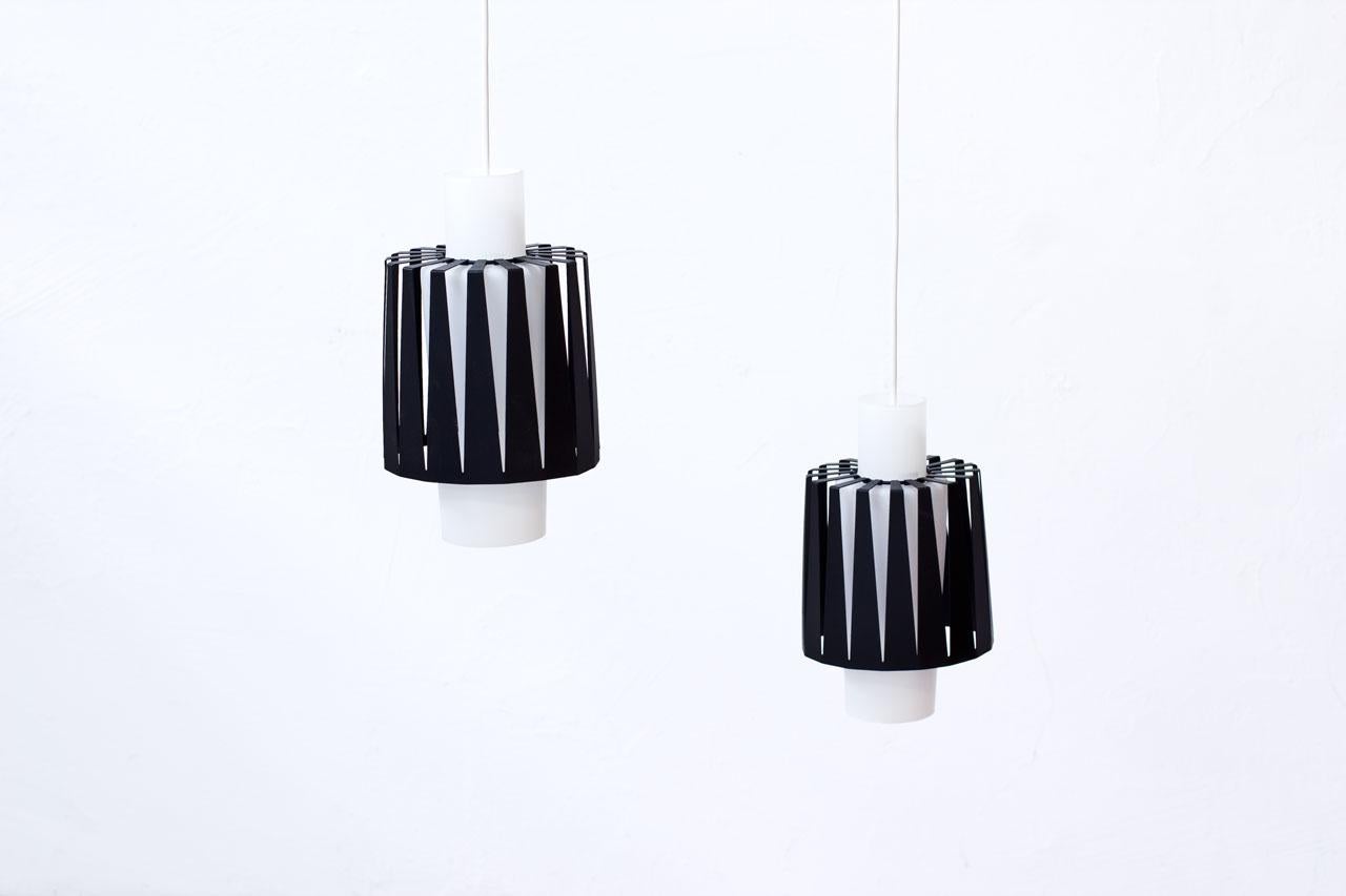 Pair of pendant lamps in opaline glass and lacquered metal. 
Metal shades are posed on the glass diffusers. 
Manufactured by ASEA in Sweden during the 1950s.