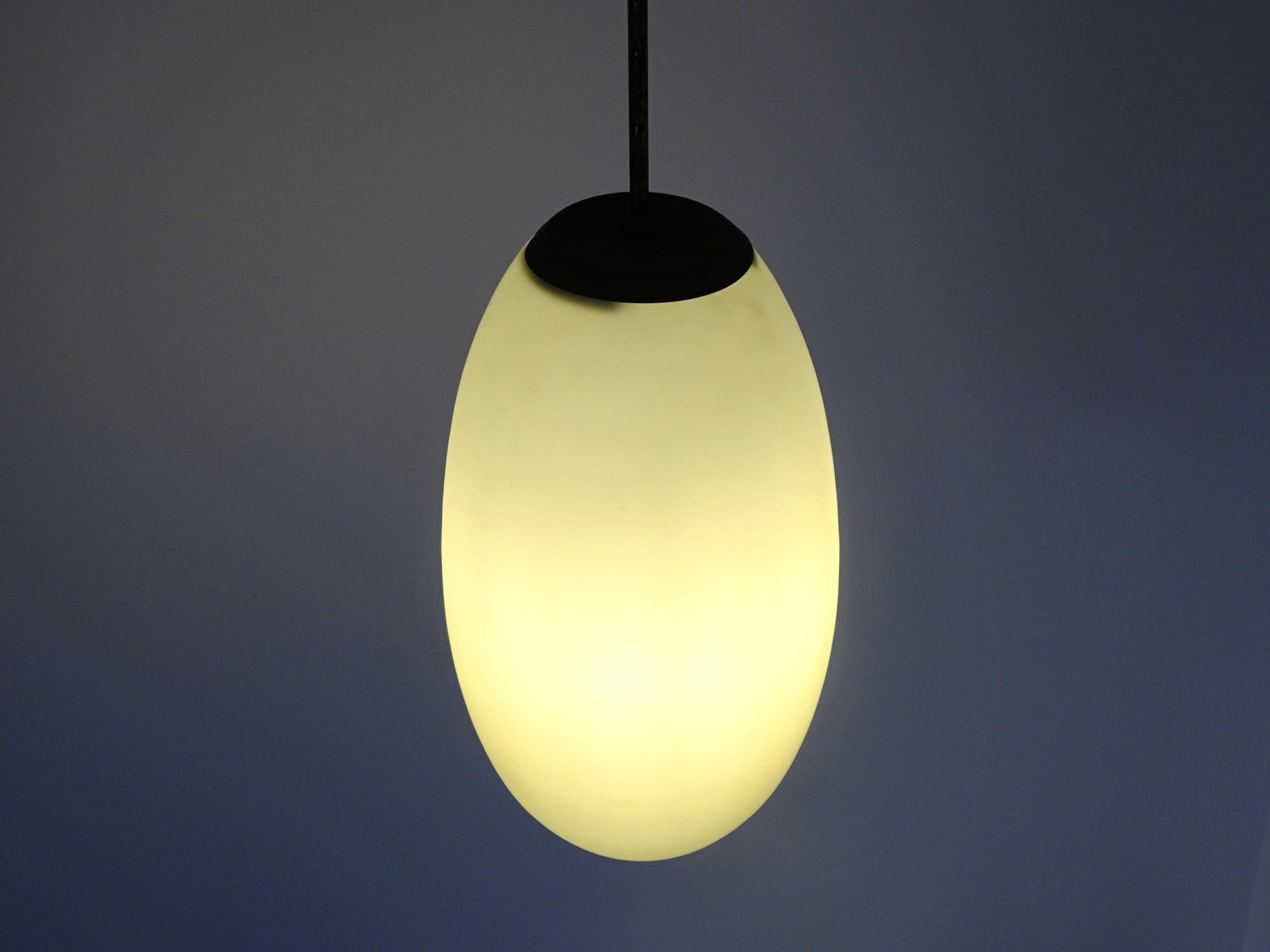 Ceiling lamp in opaline glass and brass details, with elliptical geometry.