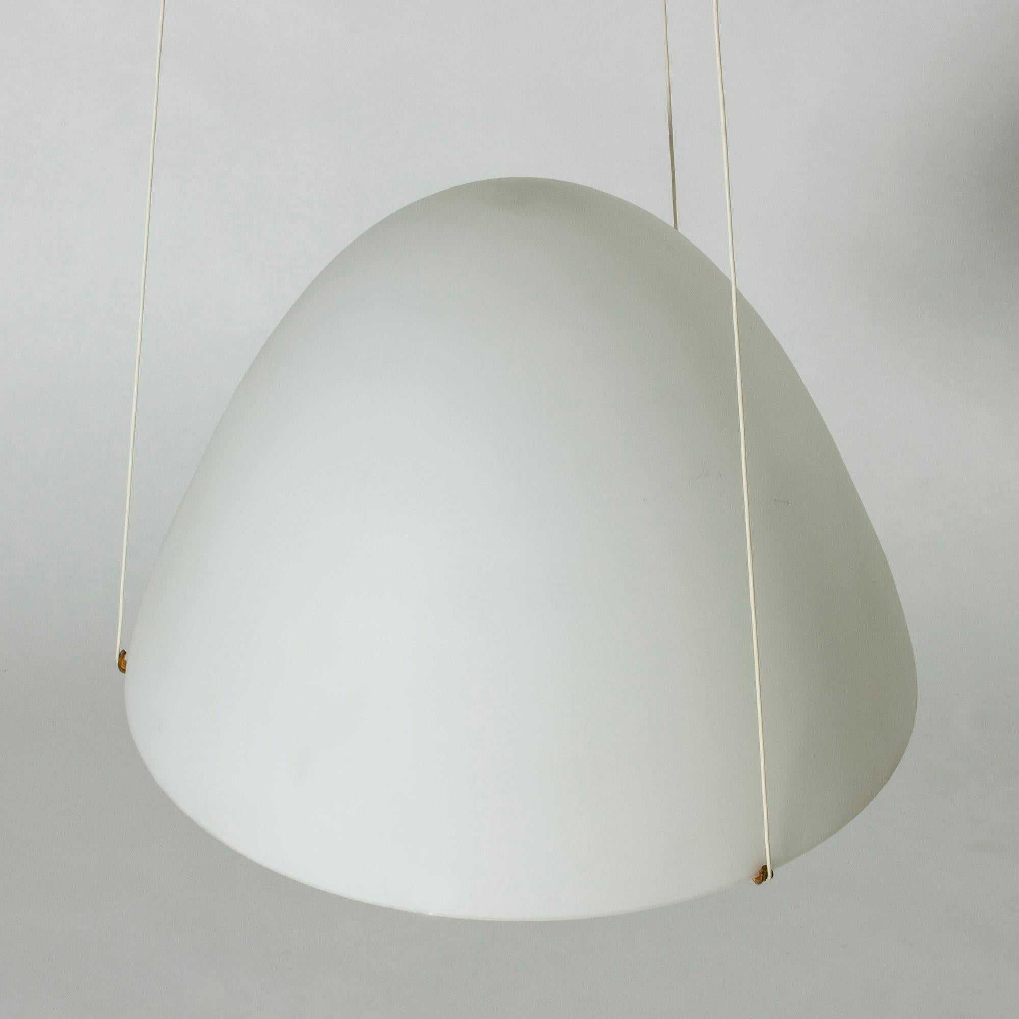 Stunning pendant light by Bertil Brisborg, made from opaline glass with brass details. The large shade is suspended on a slender brass frame whose arms the cords run through. A glass disc discreetly conceals the light source inside. Wonderful