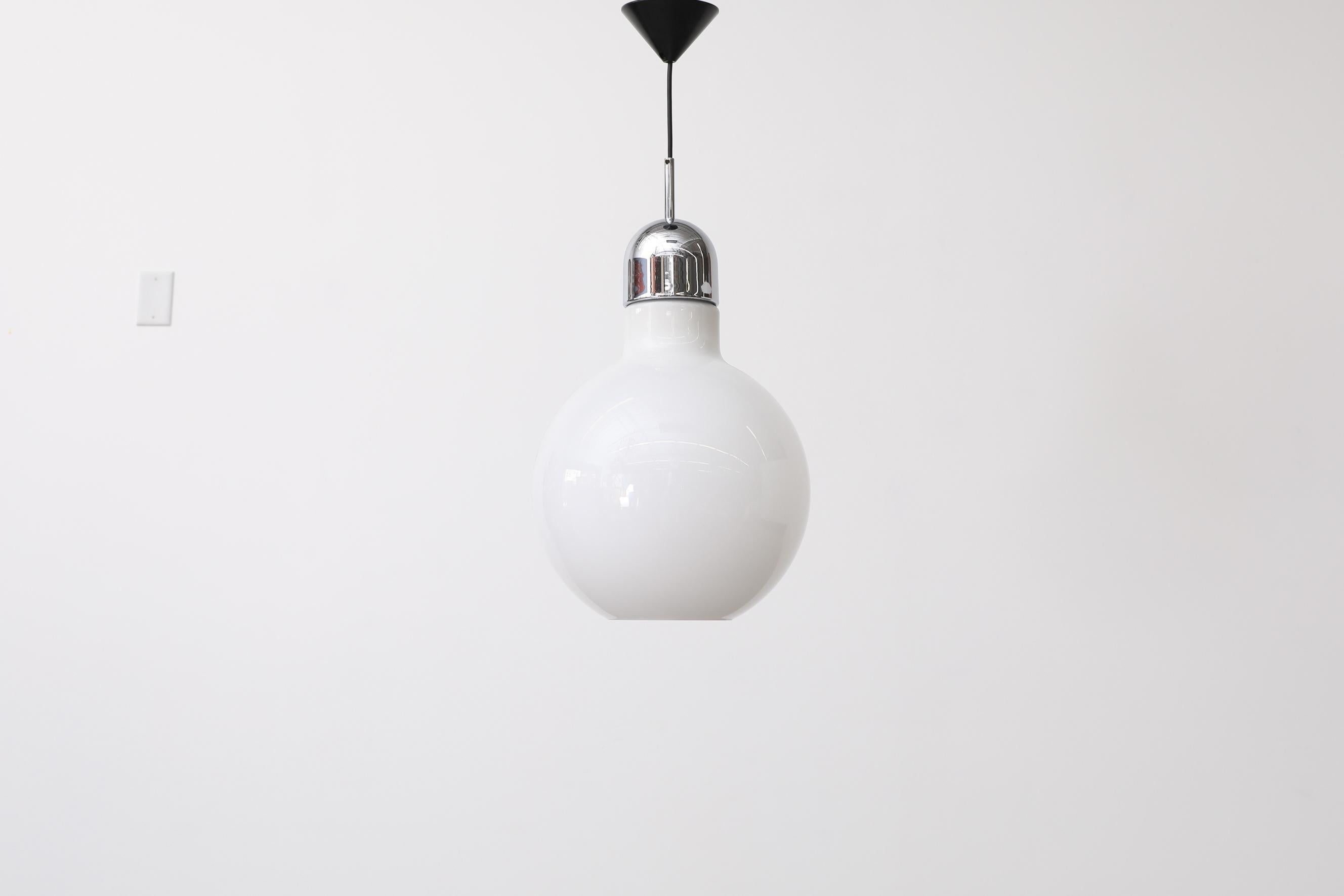 Globe pendant lamp with opaline glass bulb shaped shade. Bottom of glass globe has a circle cut out. Black plastic canopy and chrome top. In original condition with visible wear, consistent with its age and use.