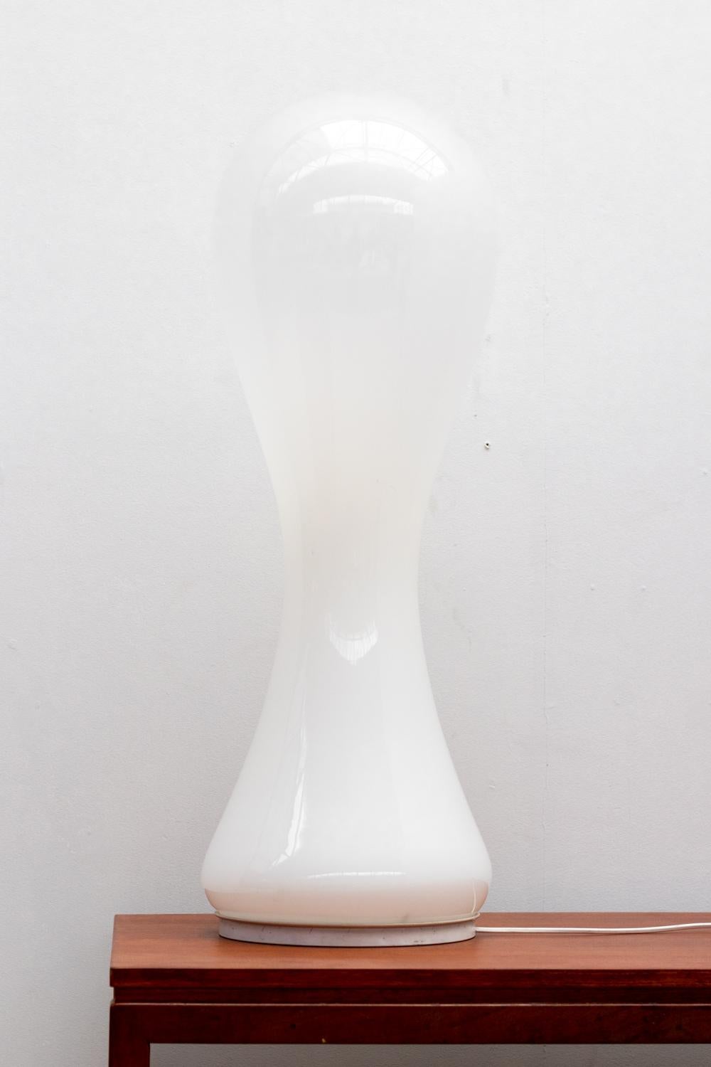 The opaline glass lamp, inspired by Italian designer Nason's style, takes the shape of a drop and sits upon a metal base. The milky glass gently curves, diffusing light softly when illuminated.

Do not hesitate to contact us for any additional