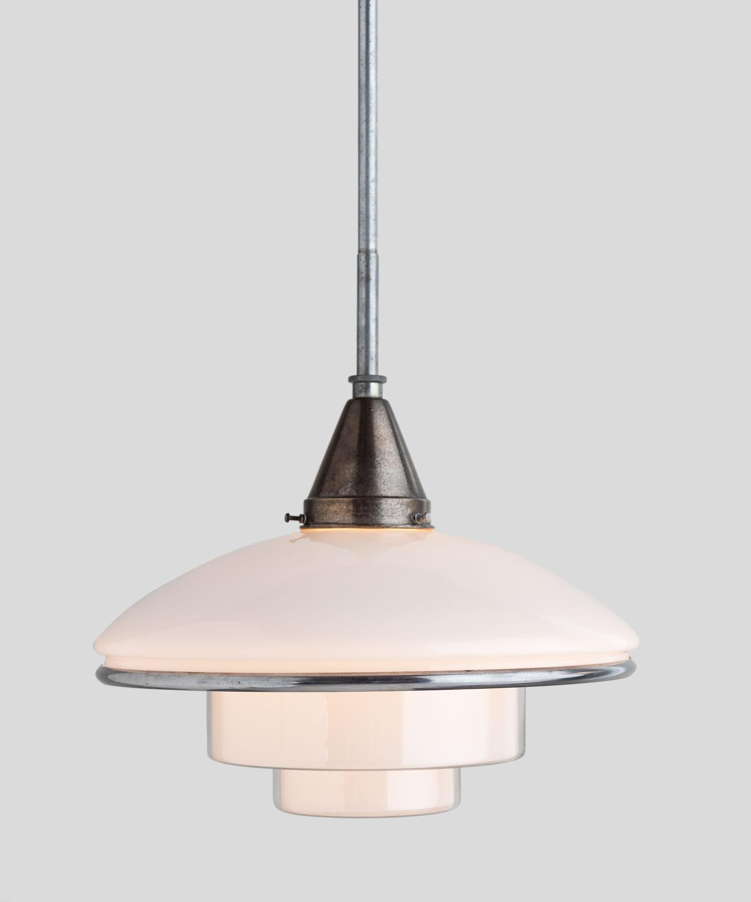 Opaline glass pendant by Otto Müller, circa 1931.

Designed by Otto Müller, manufactured by Sistrah in Germany. Composed of two main glass elements, a white opaline glass dome and an inverted ziggurat shaped opaline glass shade. Chrome-plated belt.