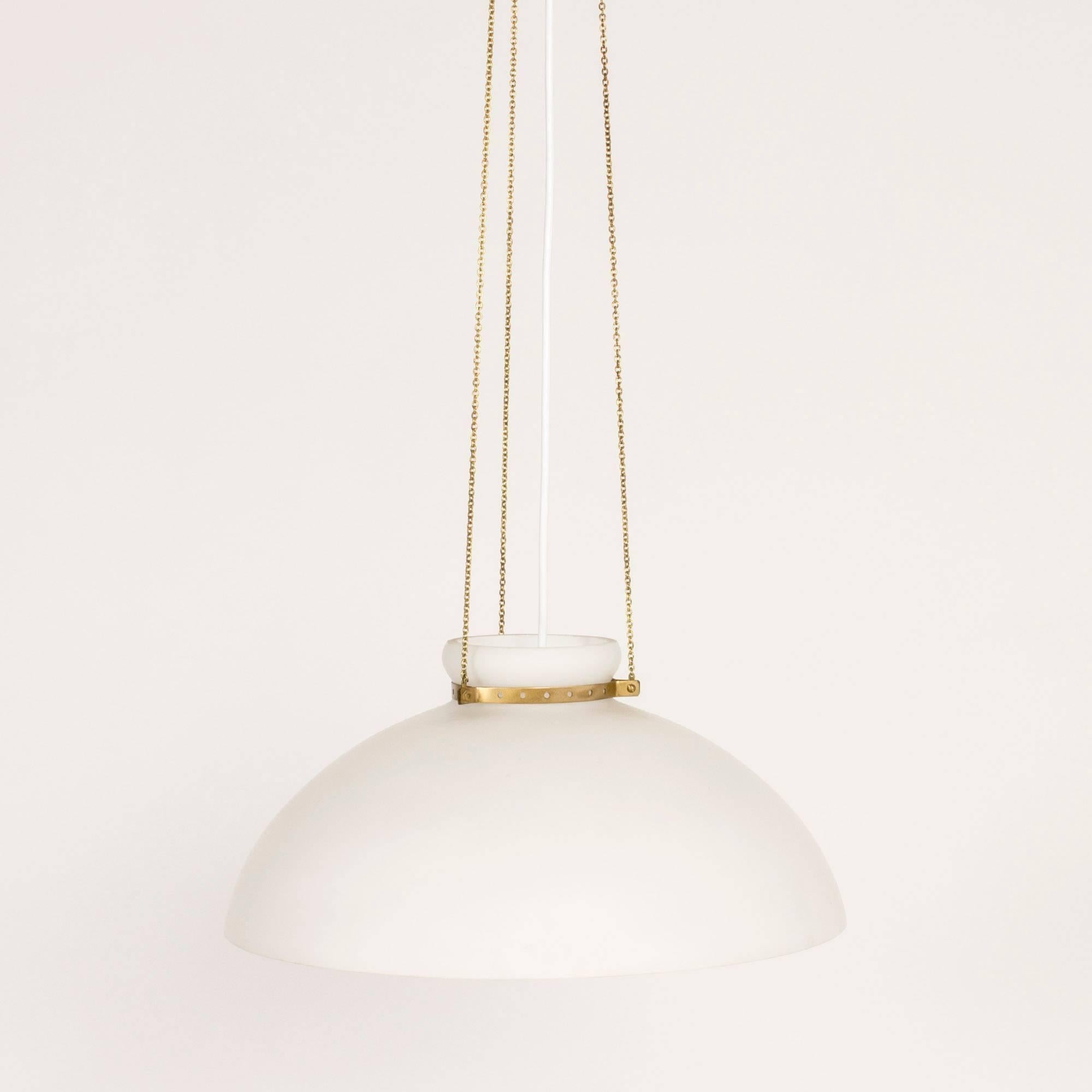 Simply elegant pendant lamp by Alf Svensson, made with an opaline glass shade suspended with slender brass chains. A slim brass strap with punched out holes encircles the neck of the lamp, holding the chains.