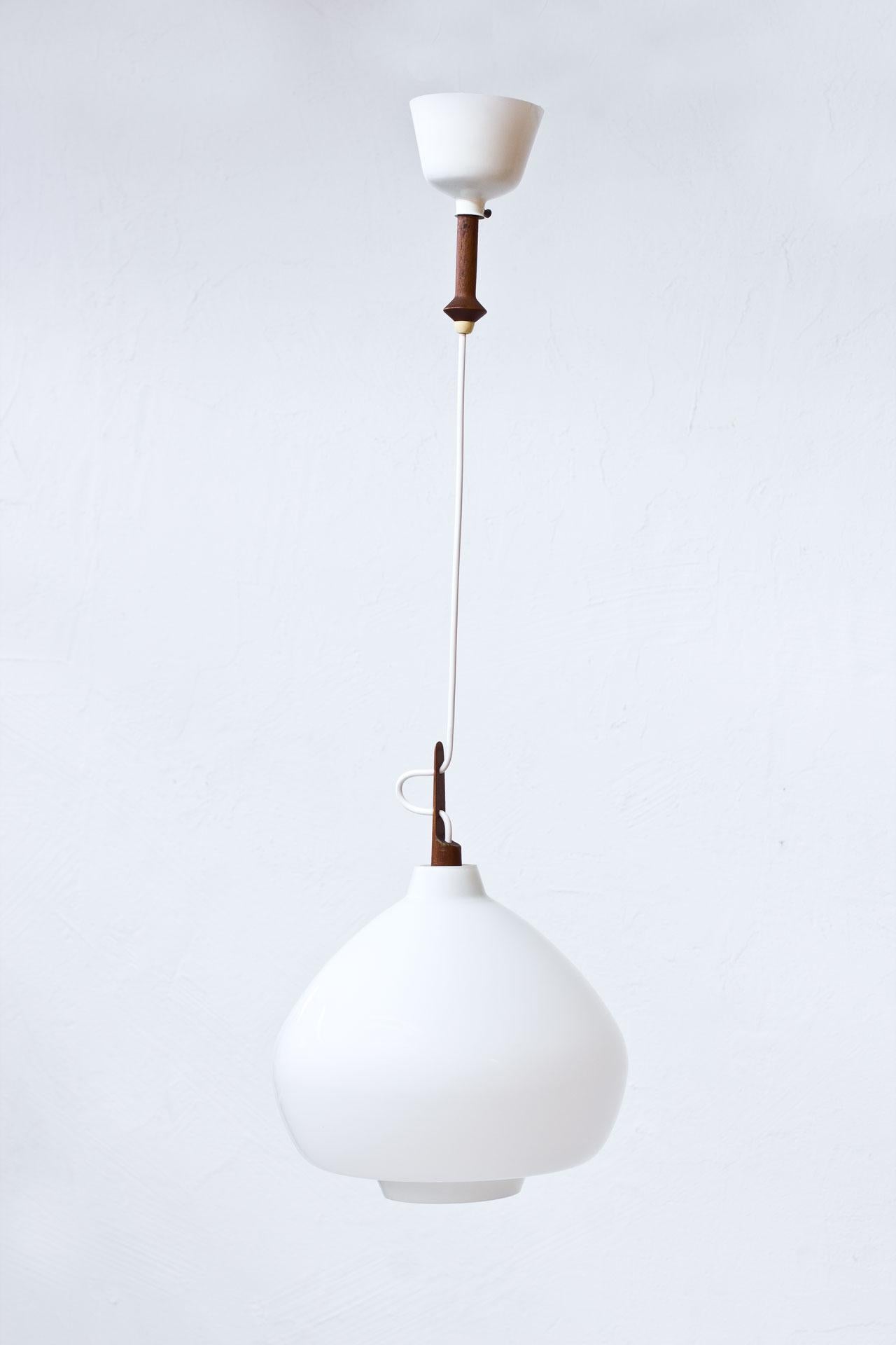 Pendant lamp designed by Hans-Agne Jakobsson. Manufactured by his own company at Markaryd, Sweden during the 1950s. Opaline glass with teak fittings. Original metal ceiling cup. New electricity.