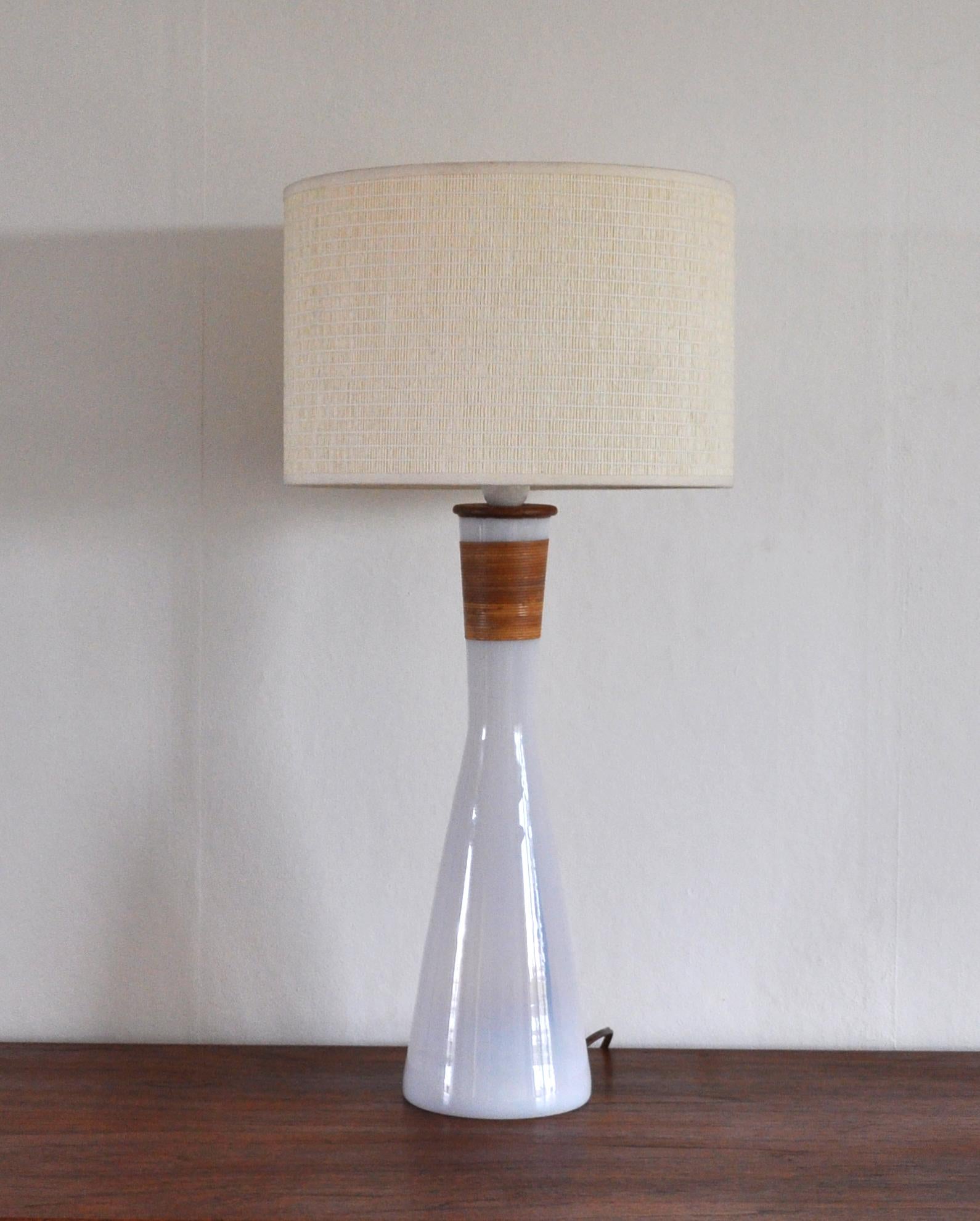 Table lamp by Jacob E. Bang in white milk glass wrapped with bamboo and teak finish. From the series Opaline, produced by Kastrup Glasværk, circa 1960. Kastrup Glasværk merged with Holmegaard in 1965.
Comes without shade.

Dimensions:
Height 59