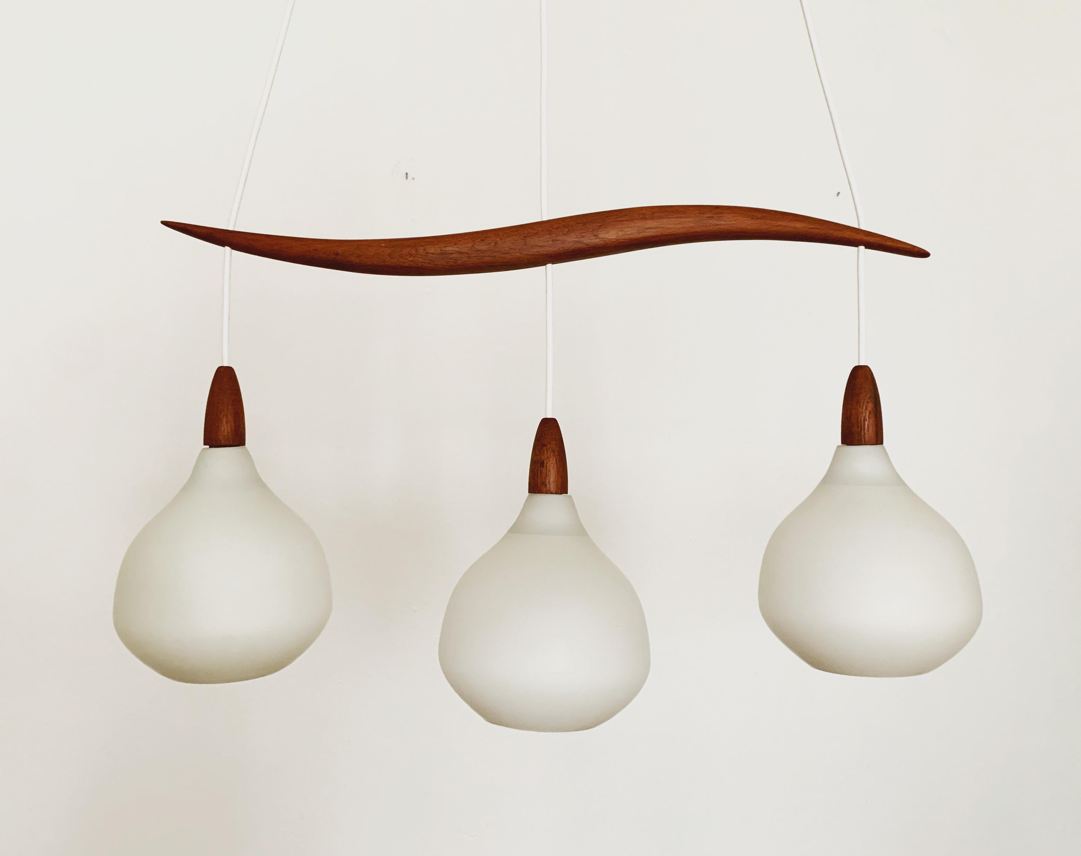 Wonderful Swedish opal glass pendant lamp from the 1960s.
Great and exceptionally minimalistic design with a fantastically elegant look.
Very nice teak details.

Manufacturer: Luxus
Design: Uno and Östen Kristiansson
Around